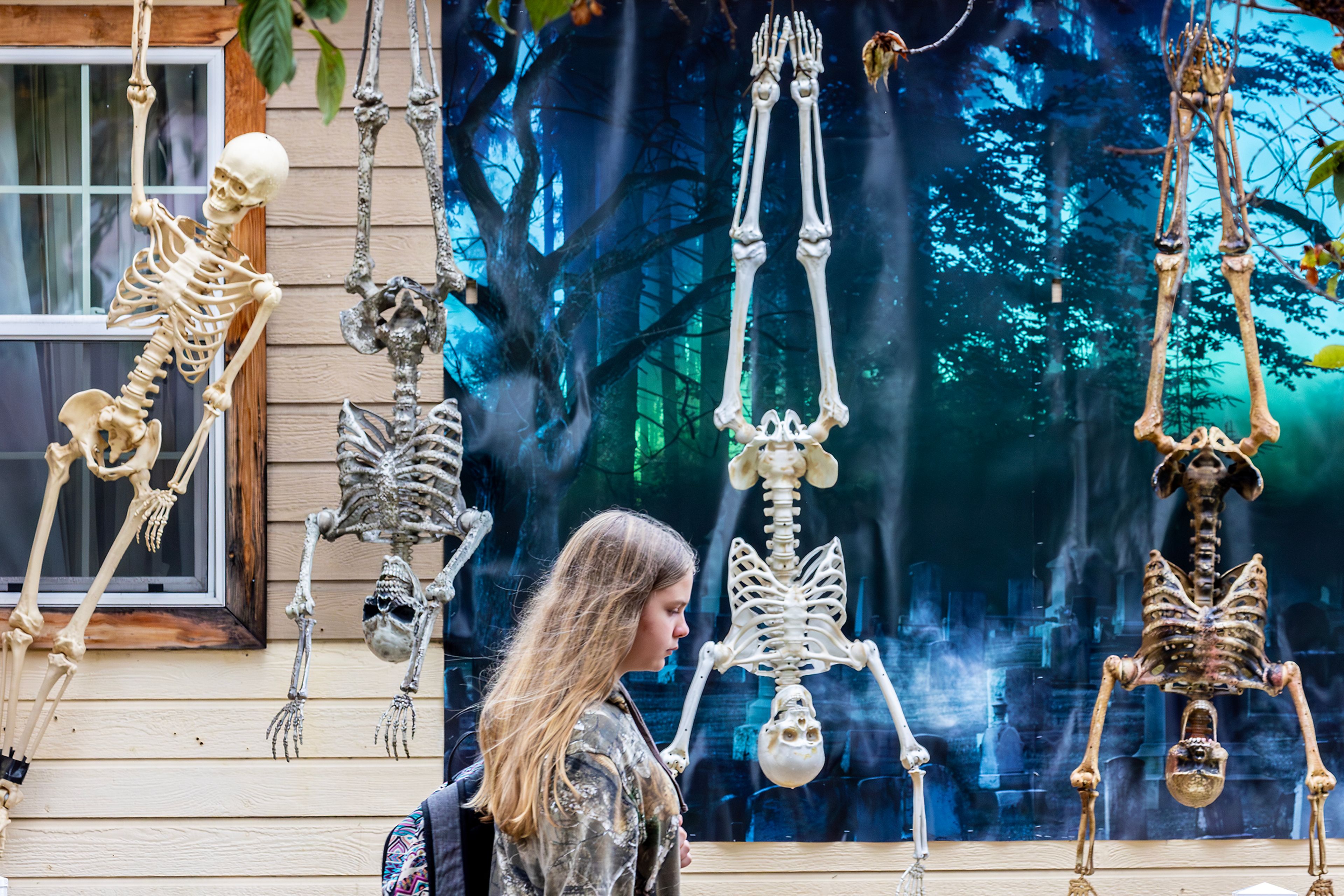 A person walks past a Halloween display of hanging skeletons Wednesday in Lewiston.