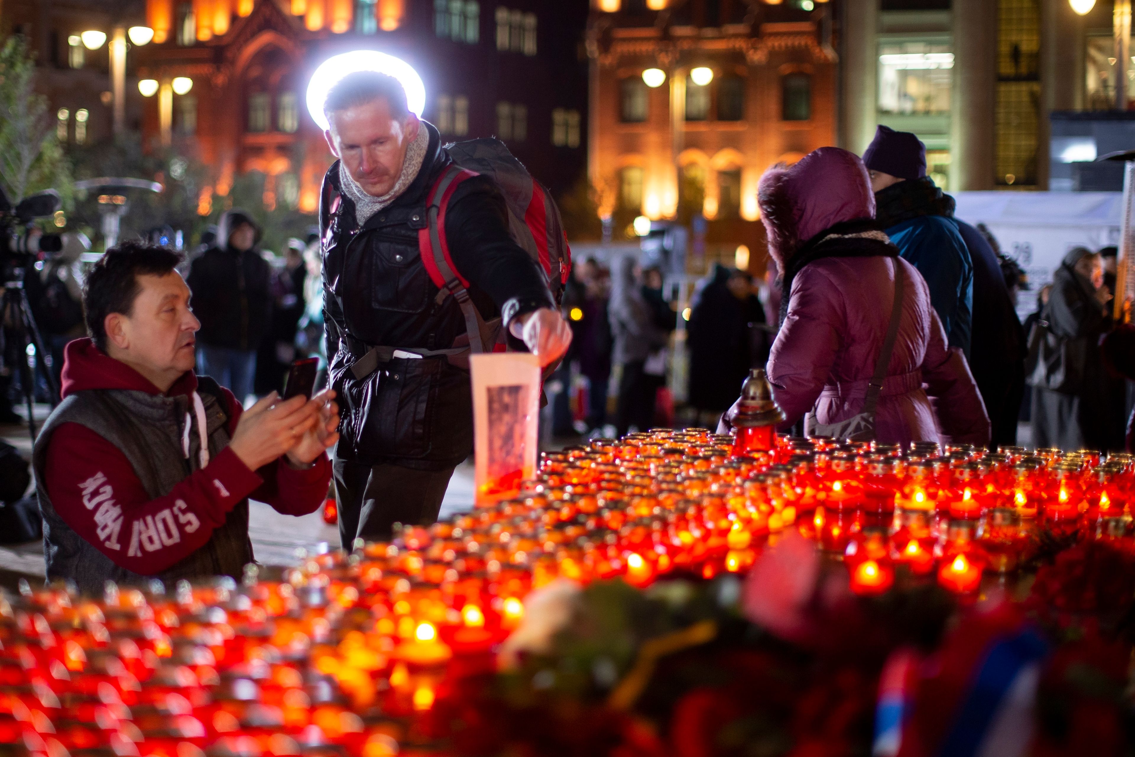 FILE - A man holds portrait of his relative, a victim of Soviet-era political repression, as other people lay flowers and light candles at a monument in front of the former KGB headquarters in Moscow, Russia, Monday, Oct. 29, 2018, in an annual commemoration of the victims of purges under Soviet dictator Joseph Stalin. Research and public debate about mass repressions by Soviet dictator Josef Stalin also have faced significant resistance in recent years. Historians and rights advocates say one reason is inevitable parallels to the ongoing government crackdown against dissent that has already landed hundreds of people behind bars. (AP Photo/Alexander Zemlianichenko, File)