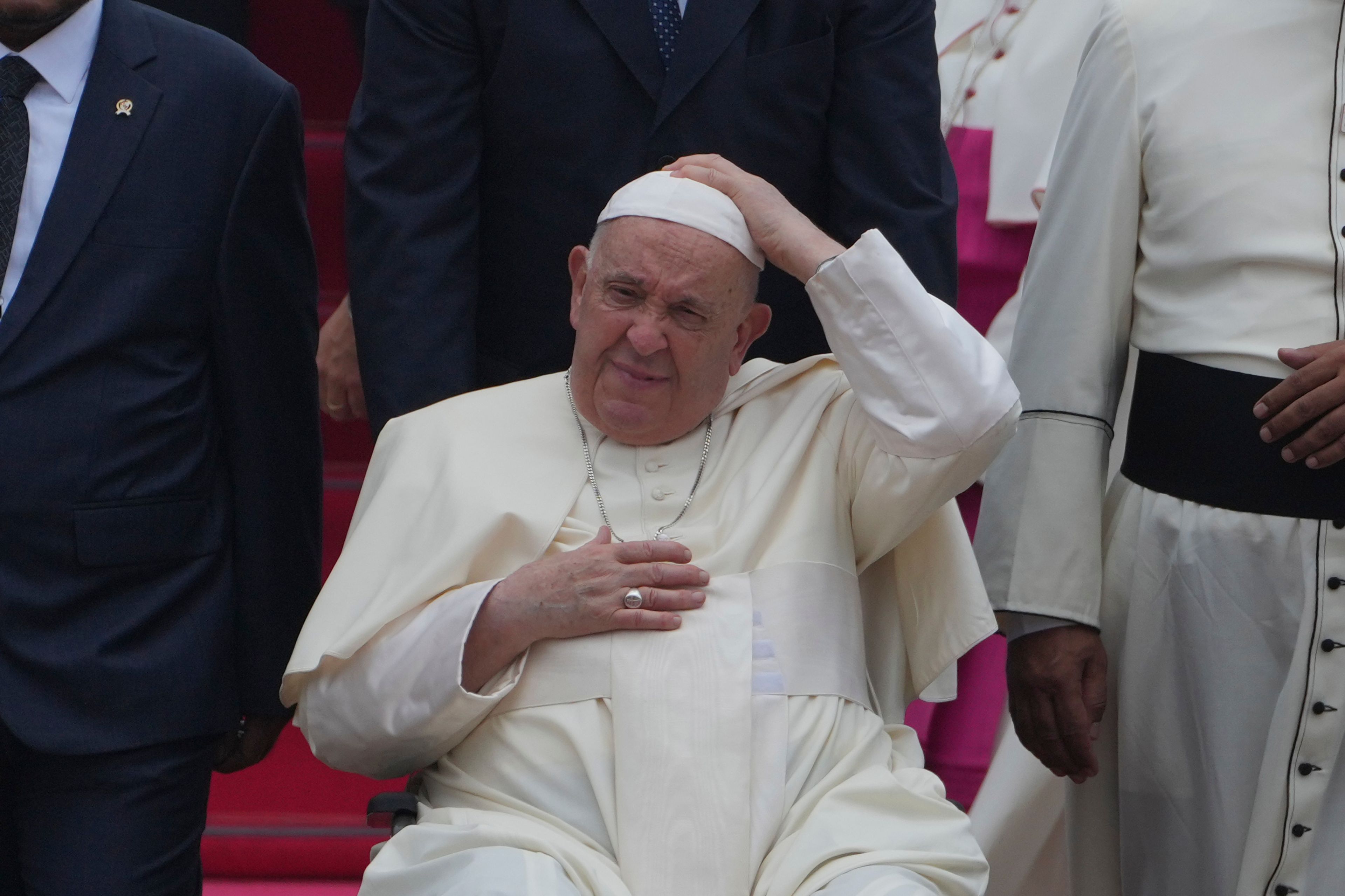 Pope Francis on his wheelchair, holds his cap upon arrival during an official welcoming ceremony at Soekarno-Hatta International Airport in Tangerang on the outskirts of Jakarta, Indonesia, Tuesday, Sept. 3, 2024.