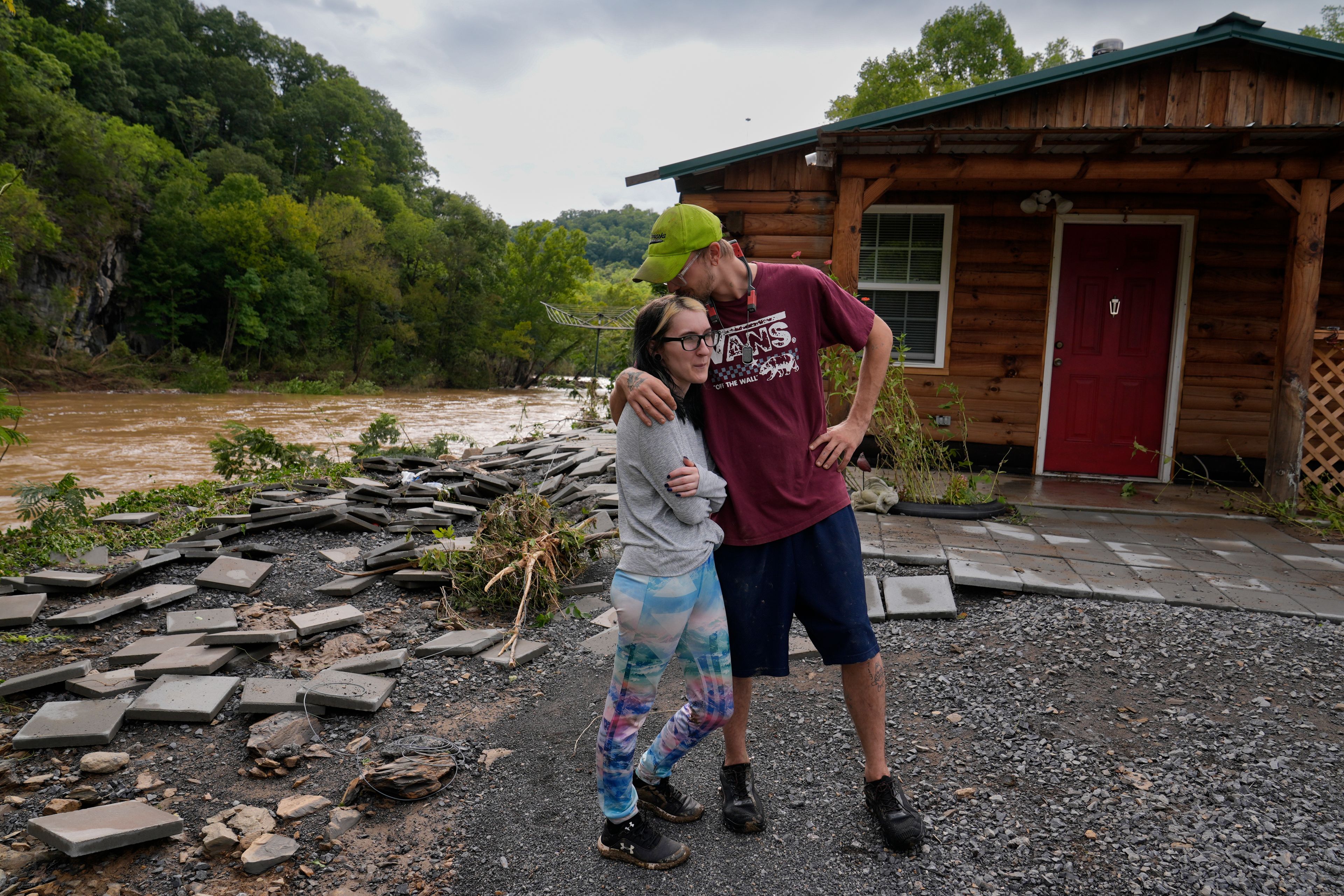 Jonah Wark, right, kisses his wife Sara Martin outside their flood-damaged home on the Pigeon River in the aftermath of Hurricane Helene, Saturday, Sept. 28, 2024, in Newport, Tenn. (AP Photo/George Walker IV)