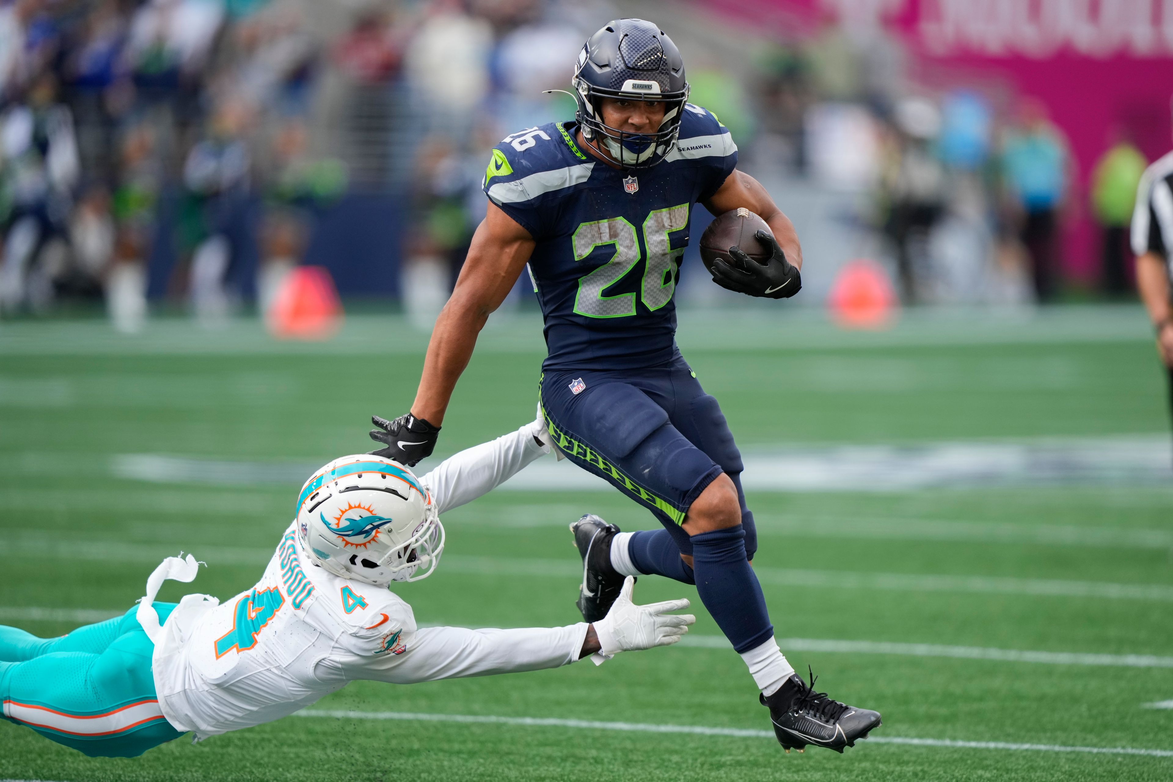 Seattle Seahawks running back Zach Charbonnet (26) runs with the ball as Miami Dolphins cornerback Kader Kohou (4) defends during the second half of an NFL football game Sunday, Sept. 22, 2024, in Seattle. (AP Photo/Stephen Brashear)