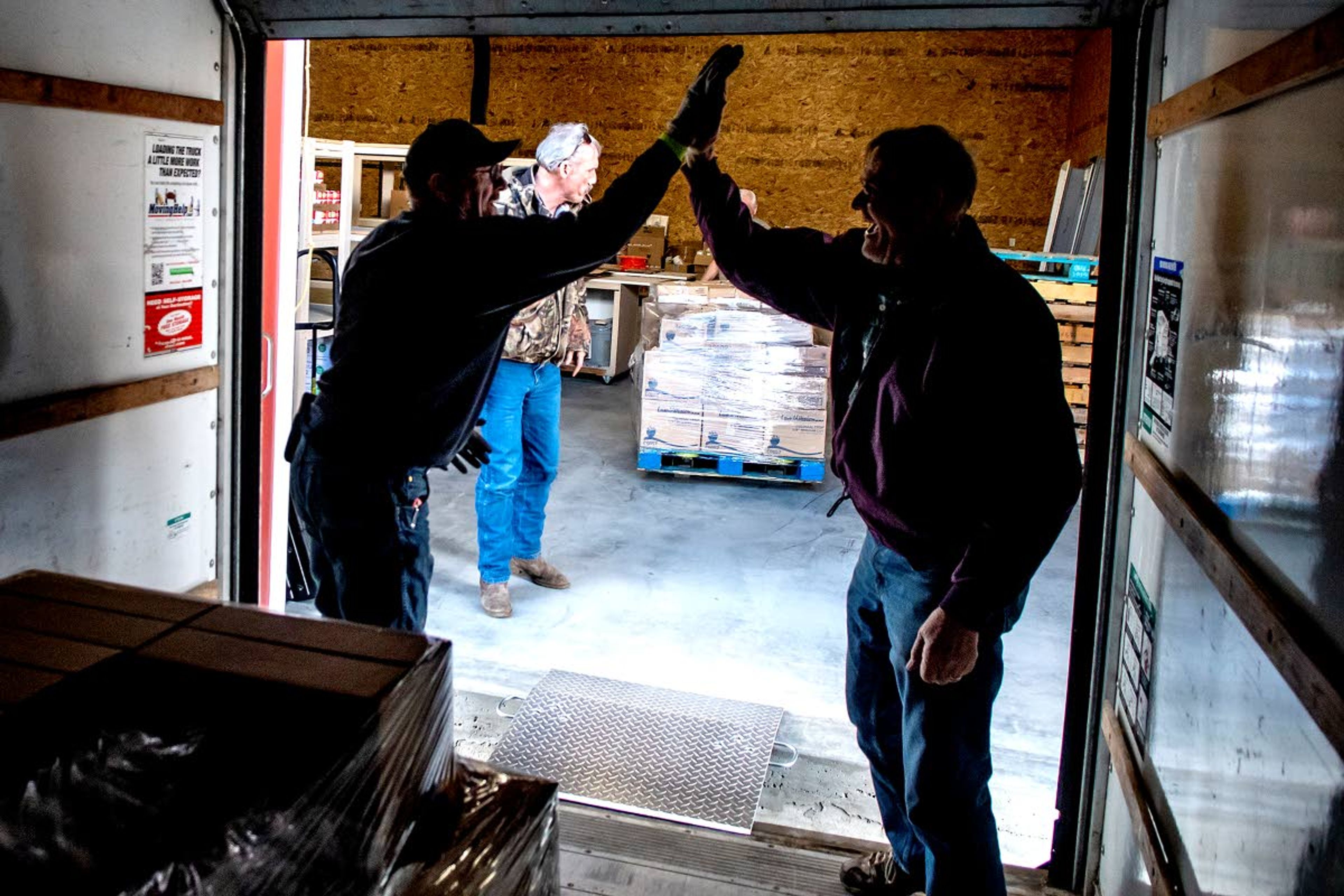 Rick Workman (left) high fives Dave Jarolimek as they unload boxes as the Camas Prairie Food Bank after it received a shipment of food from the Idaho Food Bank.