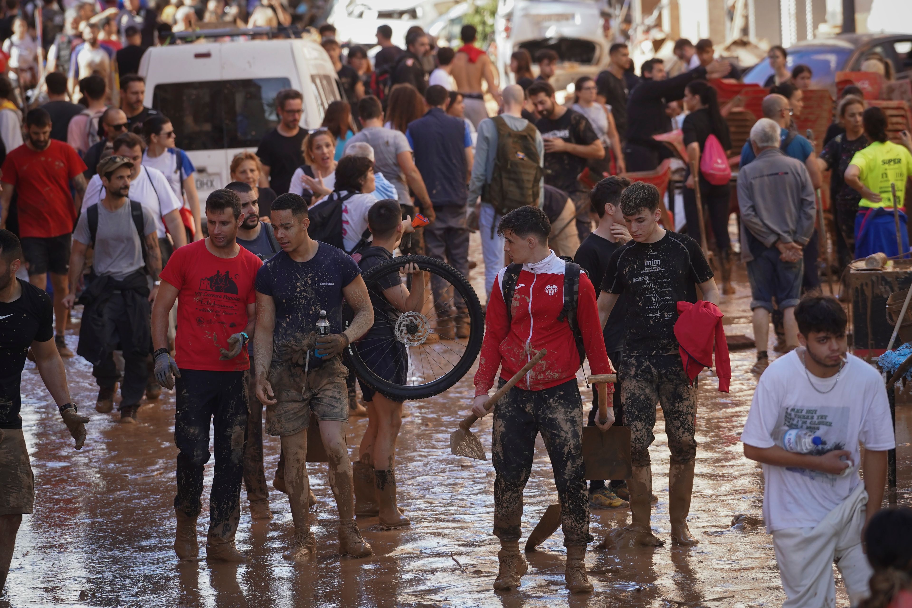 People walks through the mud at an area affected by floods in Paiporta, near Valencia, Spain, Friday, Nov. 1, 2024. (AP Photo/Alberto Saiz)