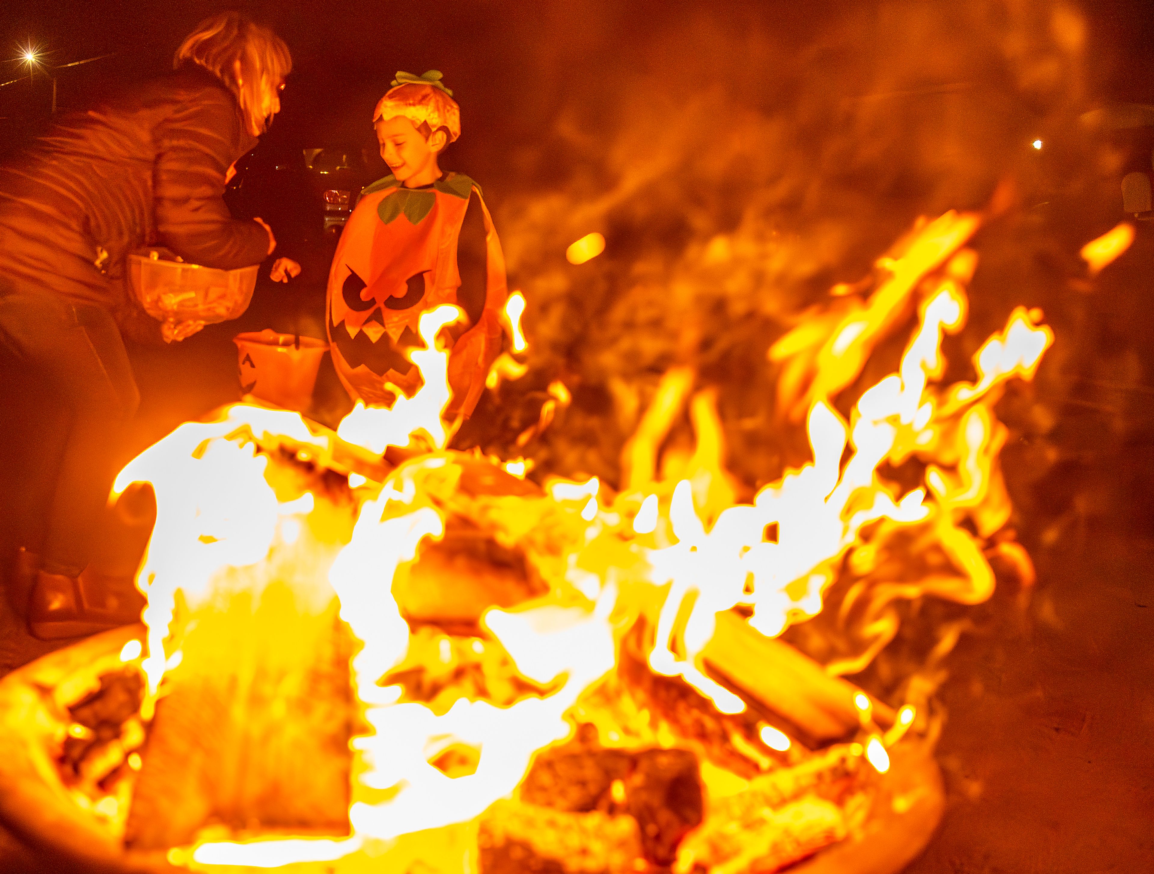 A pumpkin trick-or-treater receives some candy Thursday from Debbie Gill in the Sunset Drive neighborhood in Lewiston.