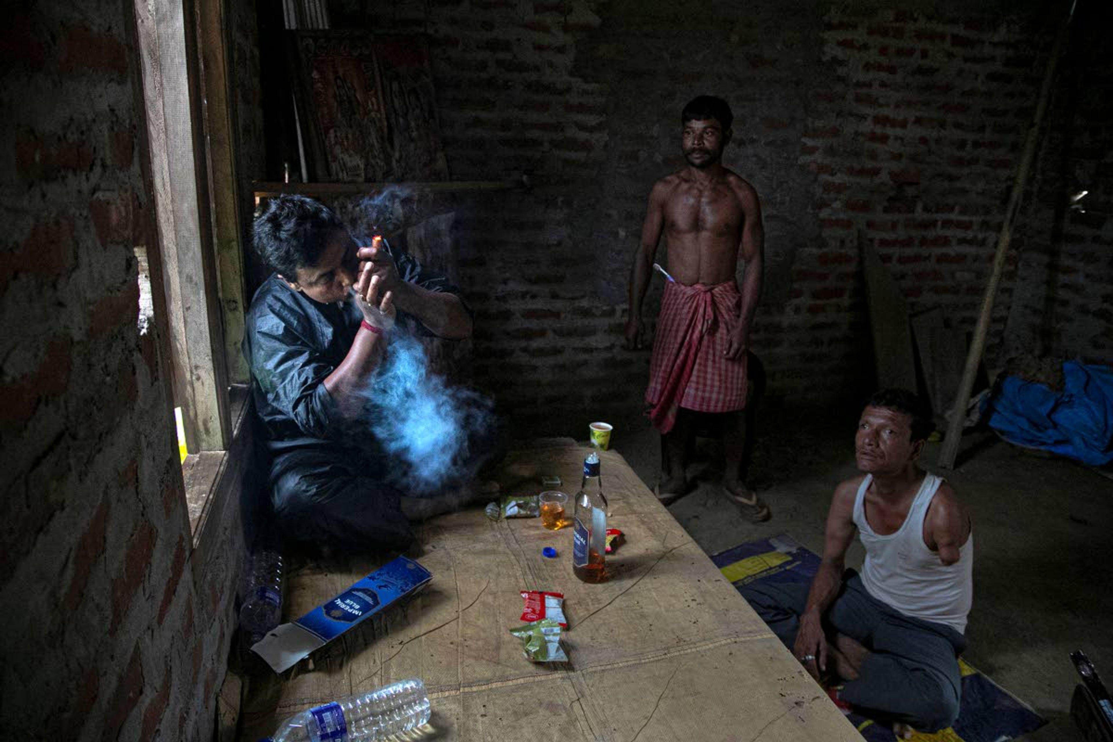 Ramananda Sarkar, 43, smokes marijuana after making a trip home to his village to meet his family, at a temple of Hindu god Shiva in Diprang village, in the northeastern Indian state of Assam, Tuesday, Sept. 22, 2020. Sarkar, who was deep in debt and desperate for money, took the job of lighting funeral pyres after failing to pay back a loan he'd taken to start selling sugarcane juice on a wooden cart. Dealing with corpses is a stigma that's only been made worse by the coronavirus, which has killed more than 100,000 people in India out of 6.4 million reported infections. After a month and a half of not seeing his wife and three sons, Sarkar snuck into his village in the middle of a recent rainy night and was able to spend 15 minutes with them and leave them some money. (AP Photo/Anupam Nath)