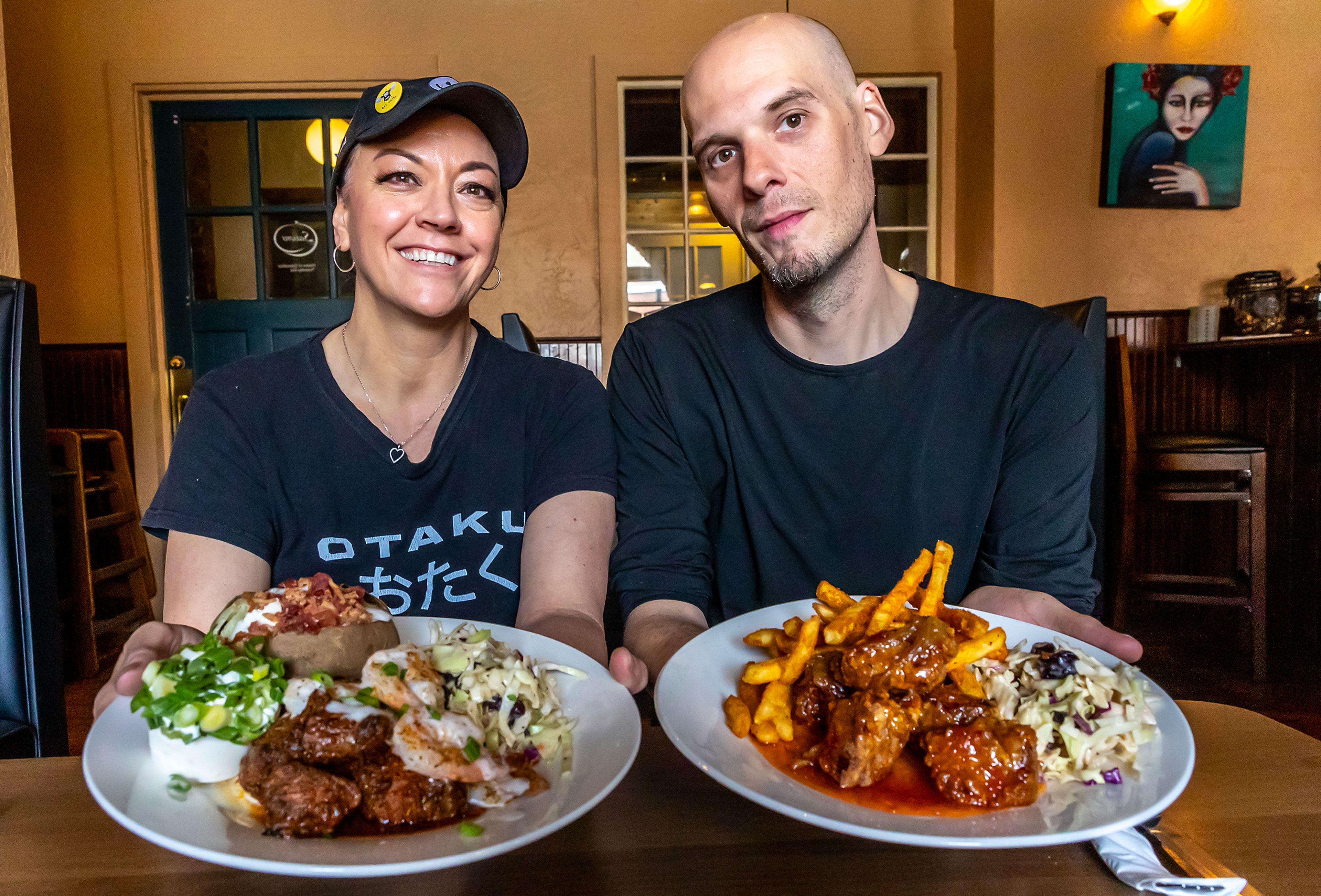 Tina Poe, left, and Ryan M Williams hold out plates of their surf and turf and sweet chili bites at Seasons Bitse and Burgers Wednesday in Lewiston.