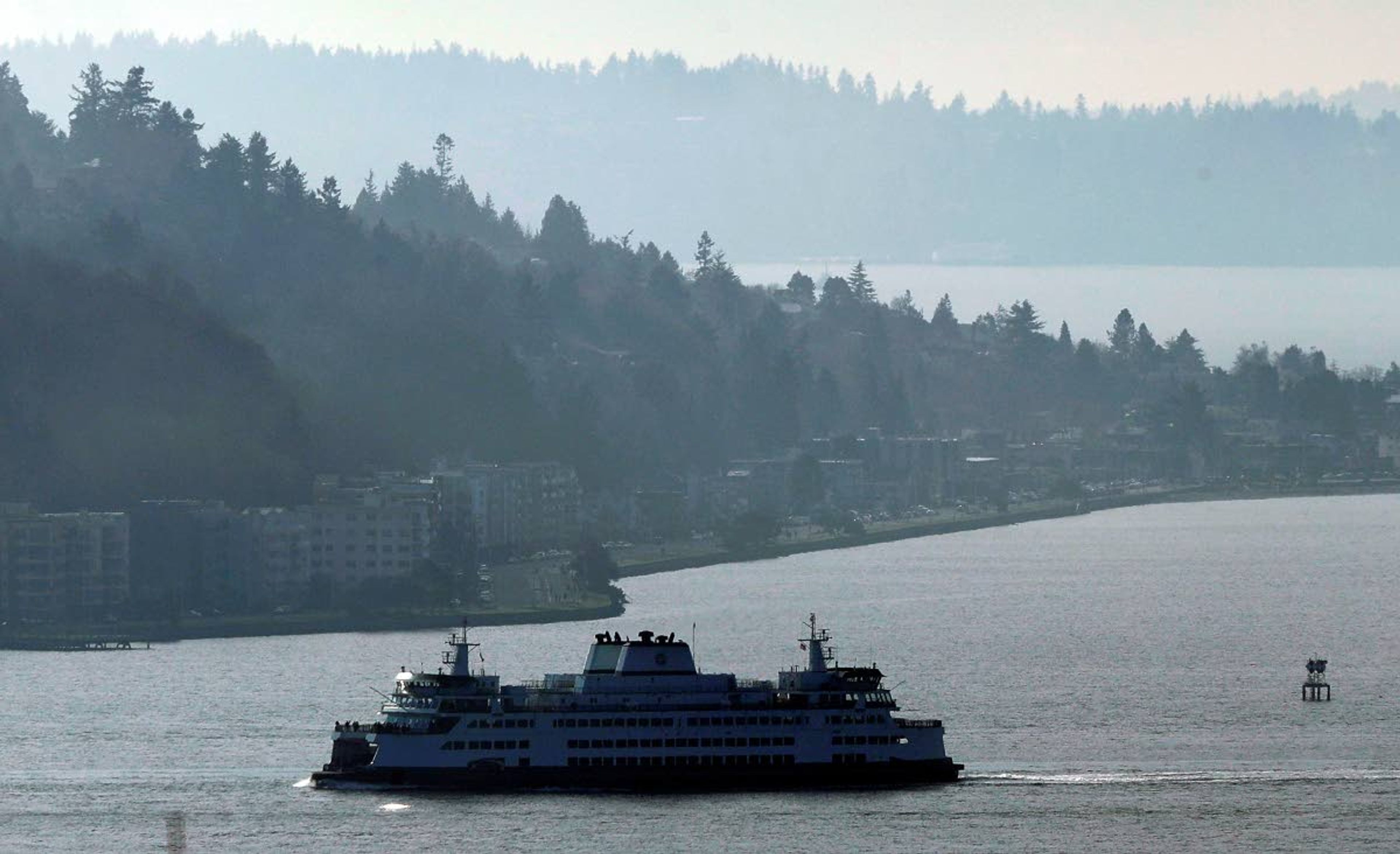 In this photo taken Dec. 31, 2018, a Washington state ferry sails on a foggy day in Elliott Bay near West Seattle. Democrats in the Washington House released their two-year transportation budget proposal Monday, March 25, 2019, which included spending for projects such as a new hybrid-electric ferry and the conversion of two others. (AP Photo/Ted S. Warren)