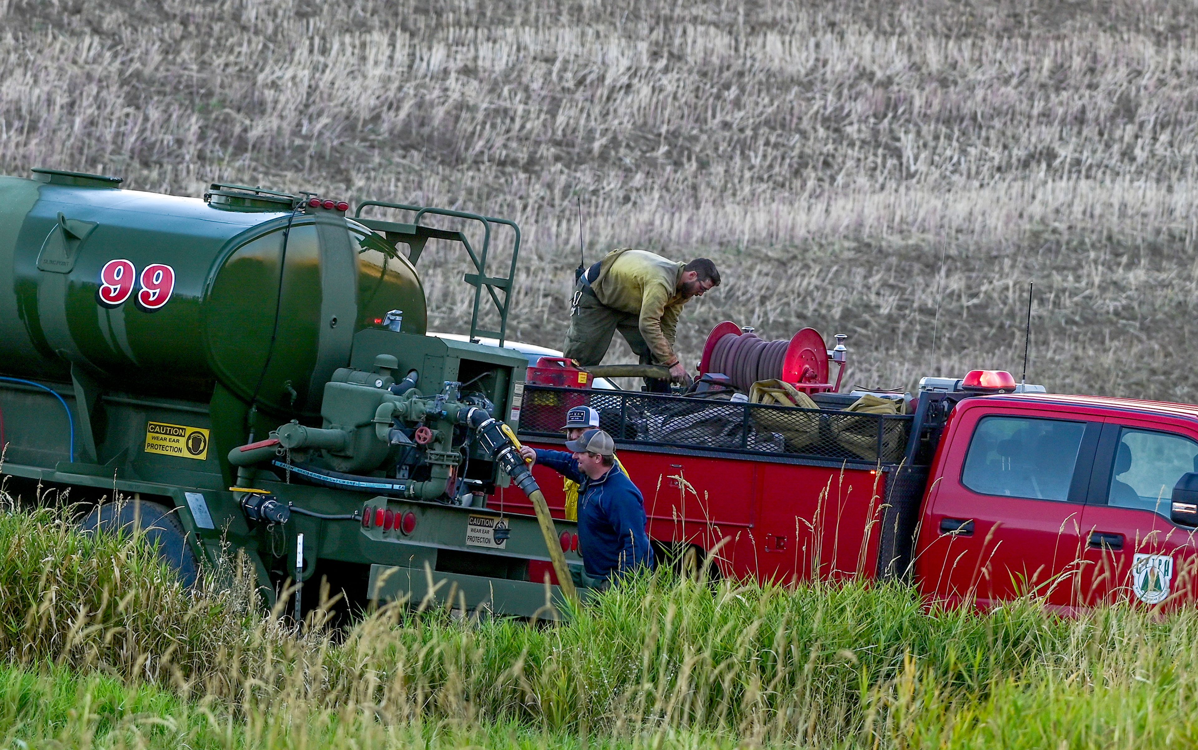 A fire truck attaches to a water tank along Teare Road as crews work to fight a wildfire Friday in Moscow.,