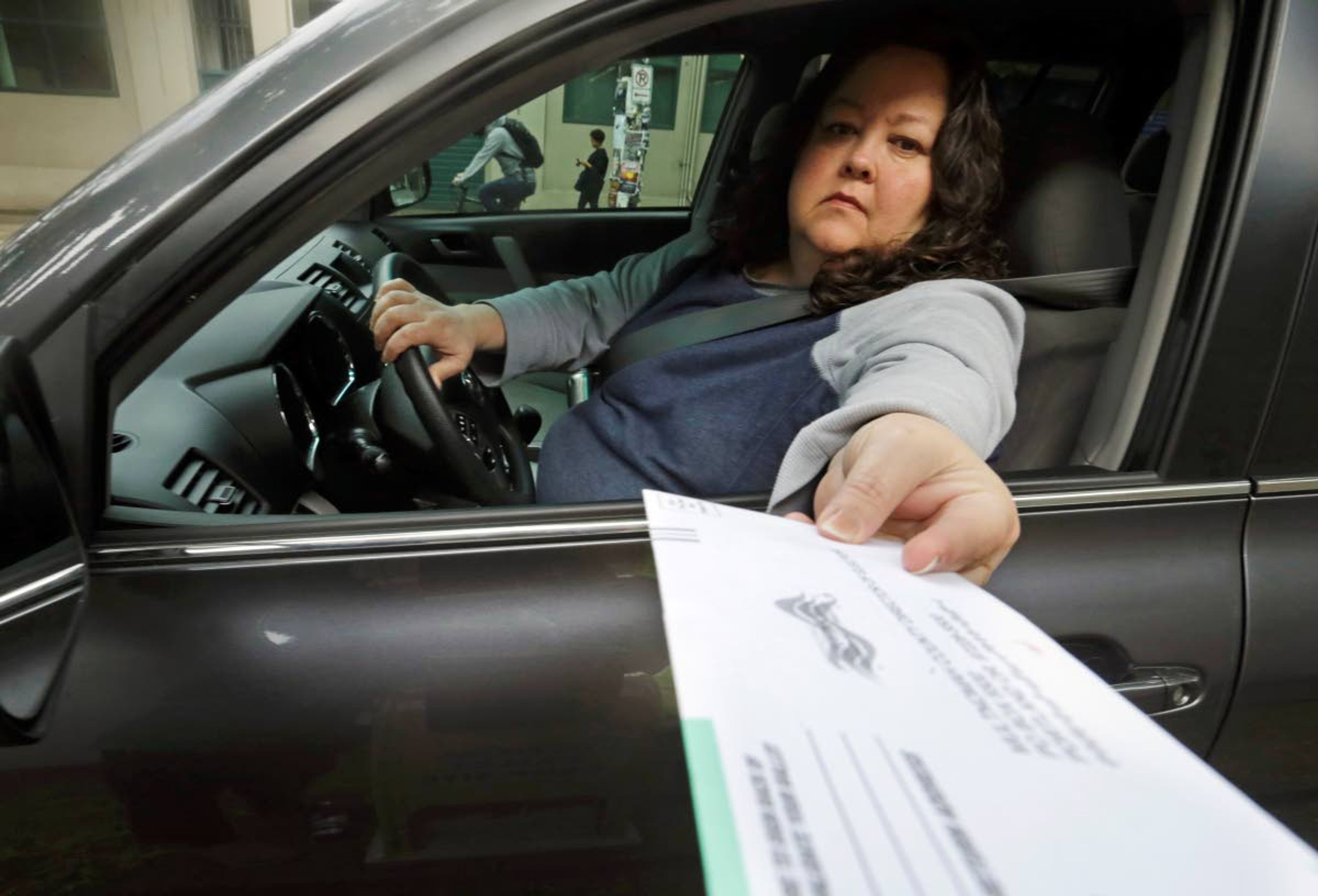 FILE - In this May 15, 2018, file photo, a voter drops off her ballot on the day of Oregon's primary election at a drive-by, drop-off station in Portland, Ore. Oregon's elections director says the voting system in the state has never been more accurate or secure, though the number of phishing attempts targeting elections officials has increased here and elsewhere. (AP Photo/Don Ryan, File)