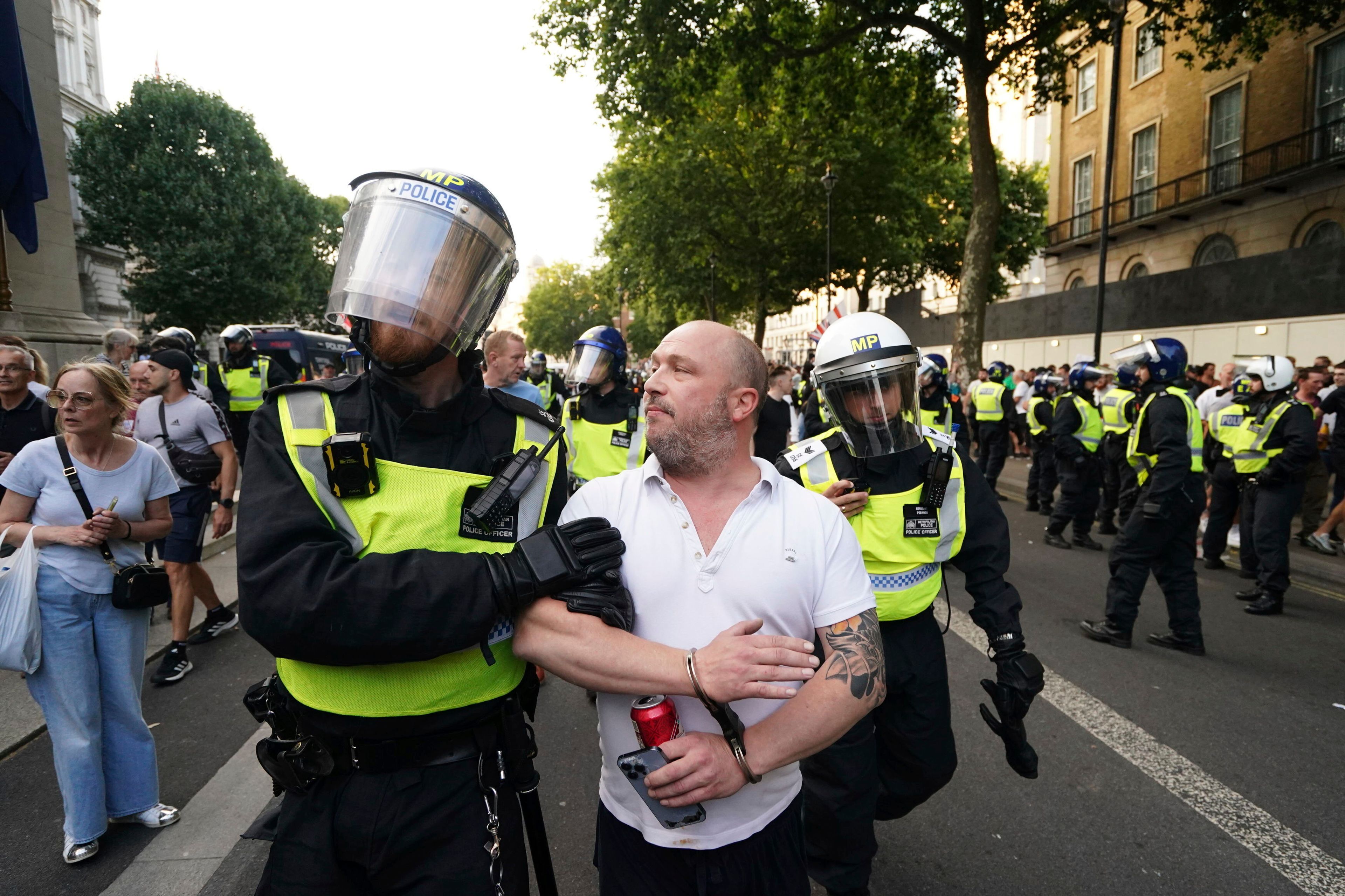 A man is detained as people attend the 'Enough is Enough' protest in Whitehall, London, Wednesday July 31, 2024, following the fatal stabbing of three children at a Taylor Swift-themed holiday club on Monday in Southport. (Jordan Pettitt/PA via AP)