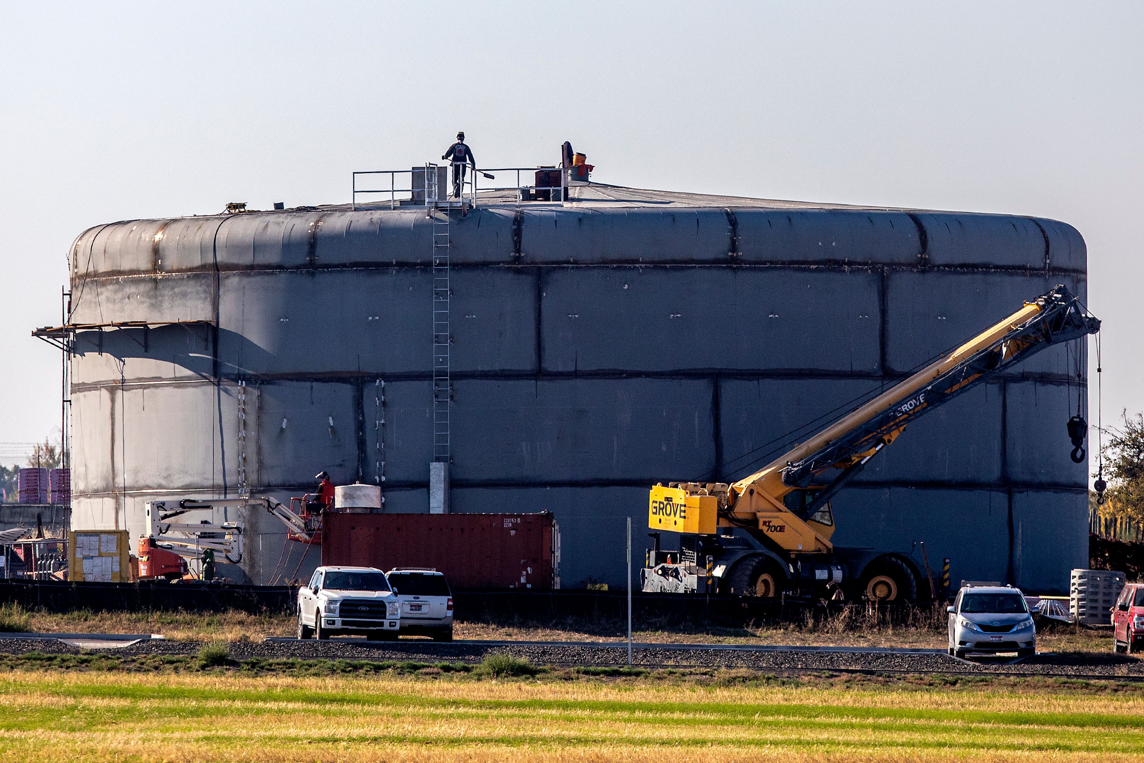 A worker walks across the roof of the new Lewiston water reservoir in the orchards nearby the high school on Wednesday, Oct. 19, 2022.