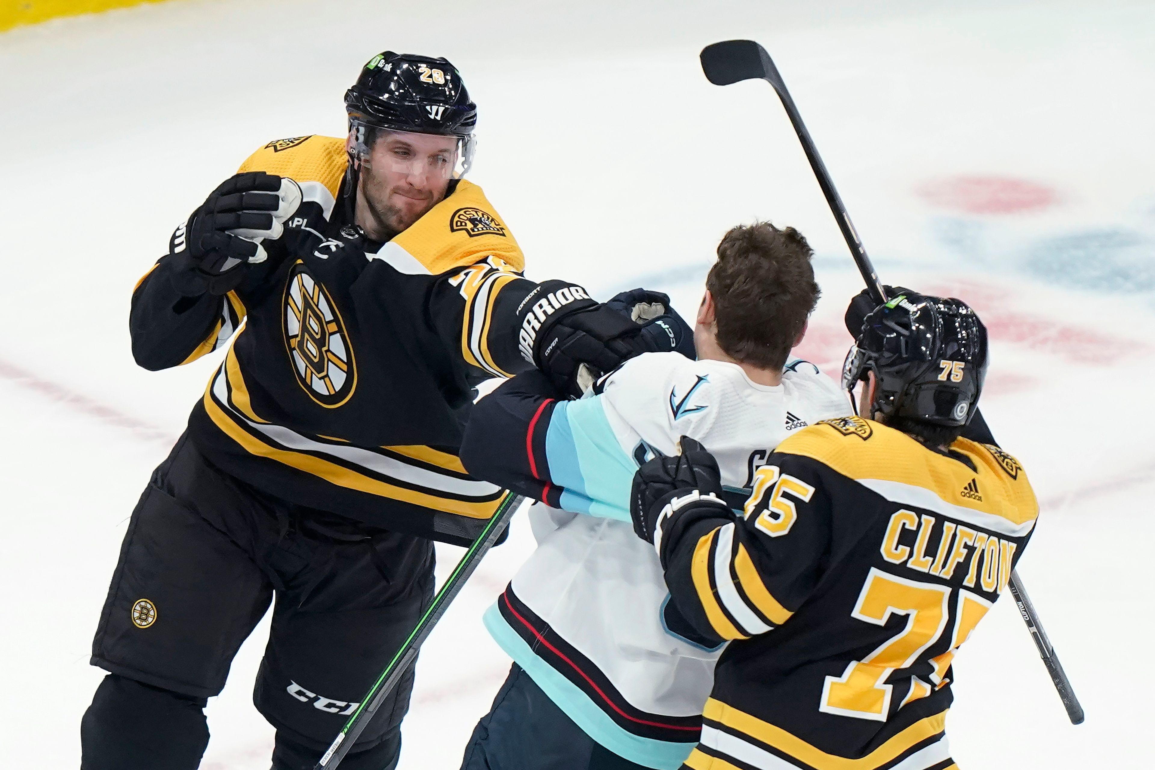 Boston Bruins defenseman Derek Forbort (28) fights with Seattle Kraken center Yanni Gourde, center, near Bruins defenseman Connor Clifton (75) during the first period on an NHL hockey game Thursday, Jan. 12, 2023, in Boston. (AP Photo/Steven Senne)