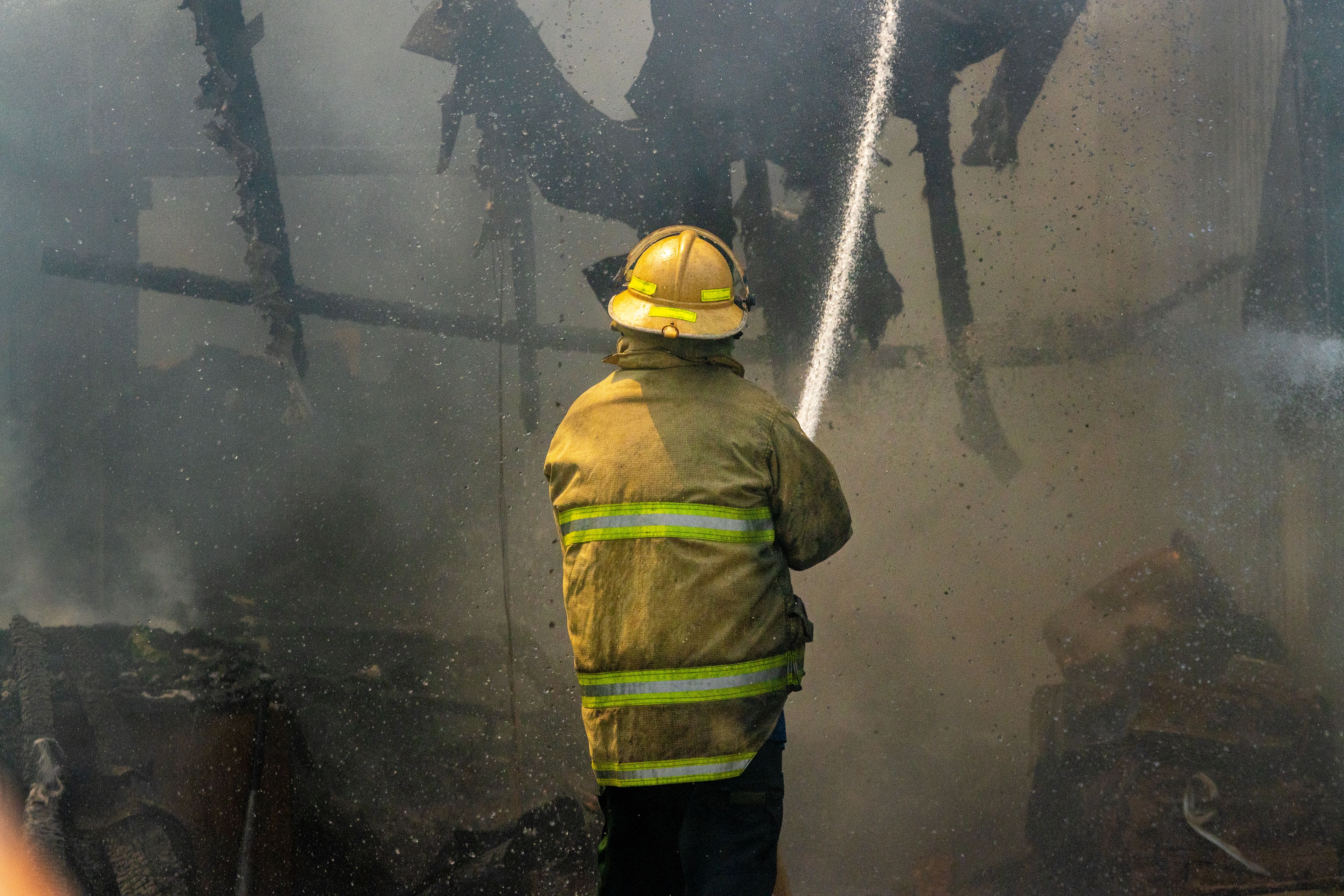 A firefighters sprays down the garage of a home at the scene of a structure fire Friday on Lolo Street in Lapwai.