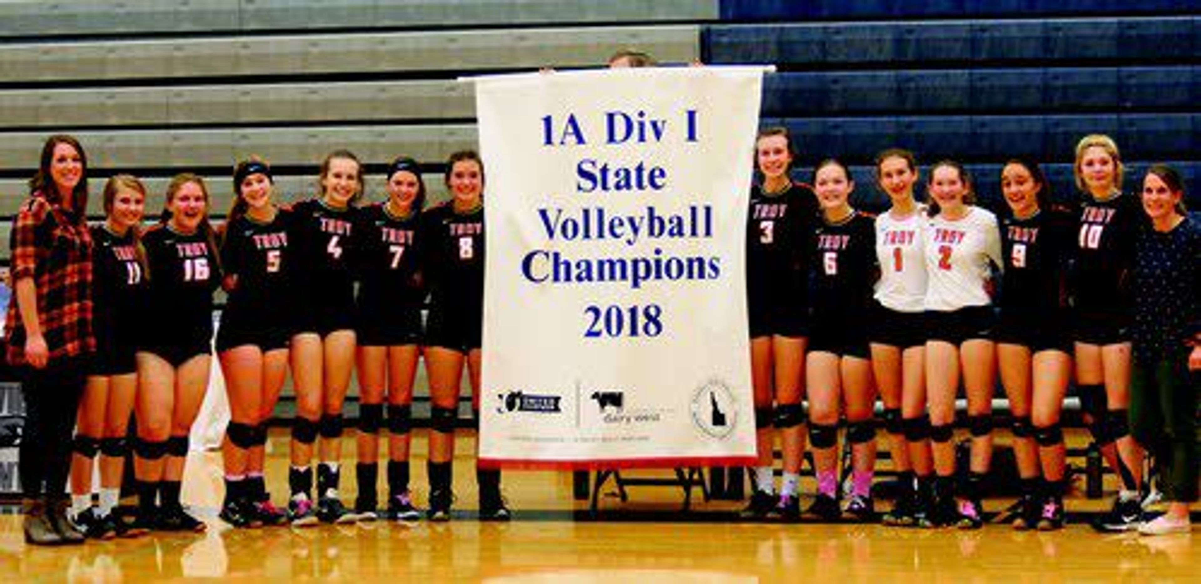 The Troy High volleyball team poses with its state championship banner, which it won Saturday at Skyview High in Nampa. In the picture (from left) are assistant coach Destry Hurst, Bailey Grove, Brenna Dunworth, Morgan Blazzard, Lindsey Kwate, Ryleigh Clemm, Jordyne Fredrickson, Taya Johnson, Loriza Atkinson, Jaycee Johnson, Katelyn Hunter, Isabelle Raasch, Lakota Anderson and coach Deborah Blazzard.