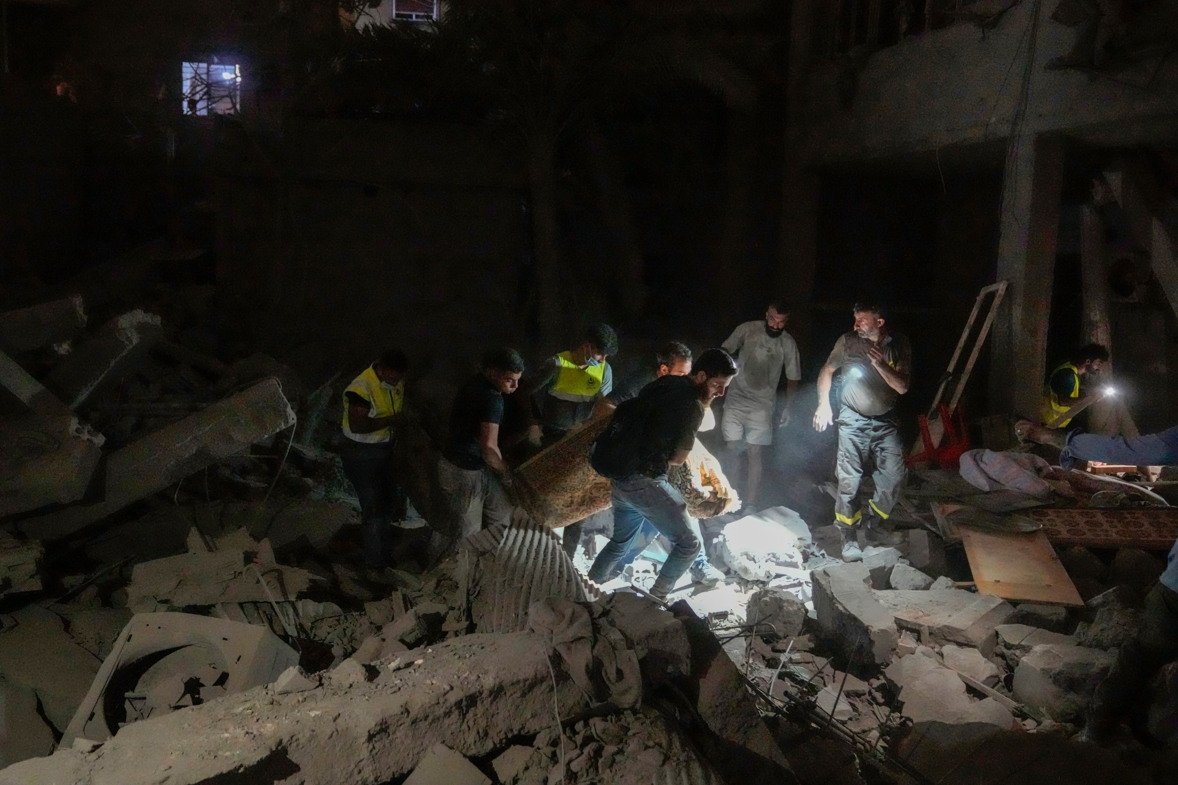 People carry a body at the scene of destroyed buildings hit by an Israeli airstrike in central Beirut, Lebanon, Thursday, Oct. 10, 2024. (AP Photo/Bilal Hussein)