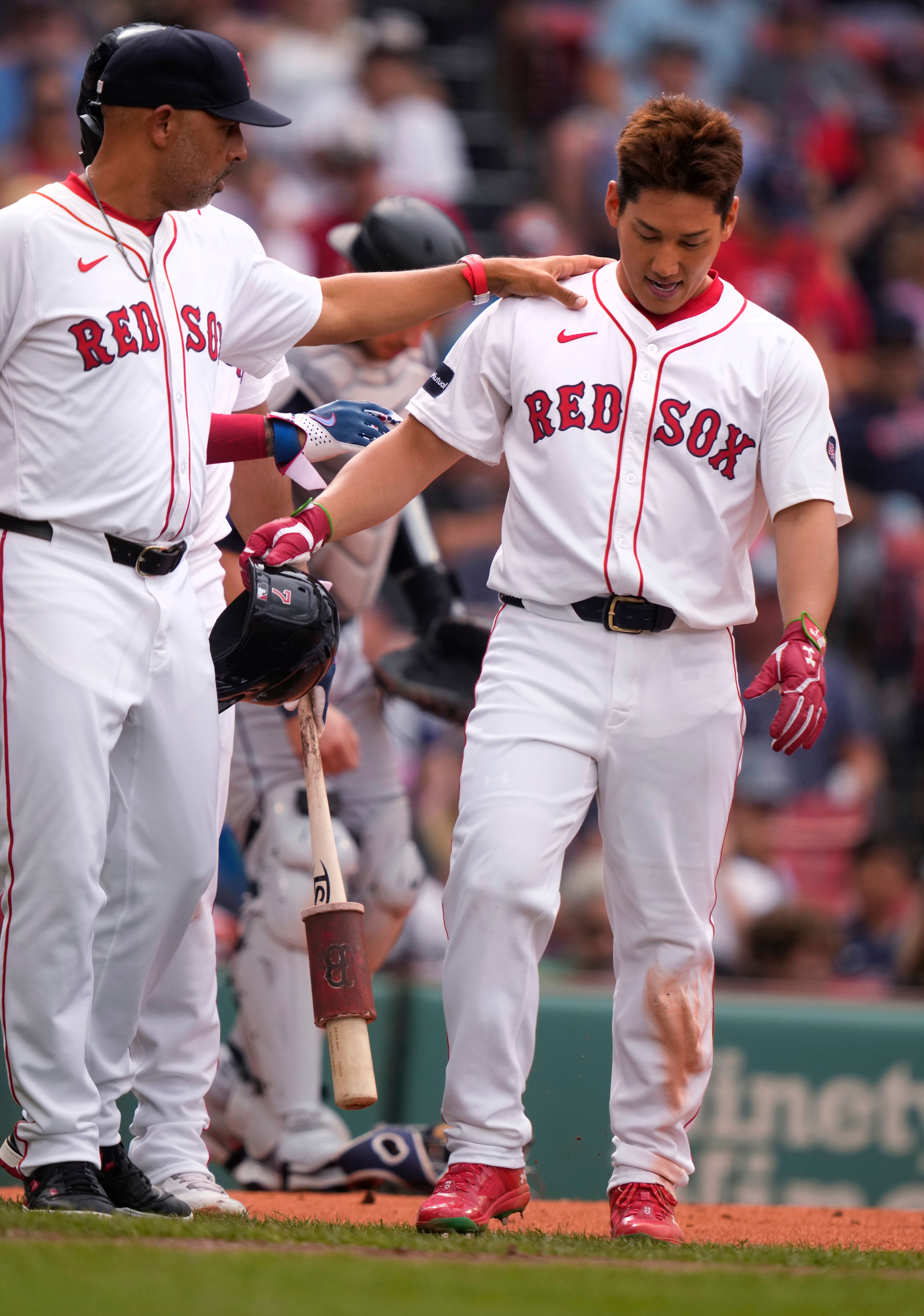 Boston Red Sox's Masataka Yoshida, right, is helped by manager Alex Cora after colliding with Seattle Mariners pitcher George Kirby, while scoring on a wild pitch during the first inning of a baseball game, Wednesday, July 31, 2024, in Boston. (AP Photo/Charles Krupa)