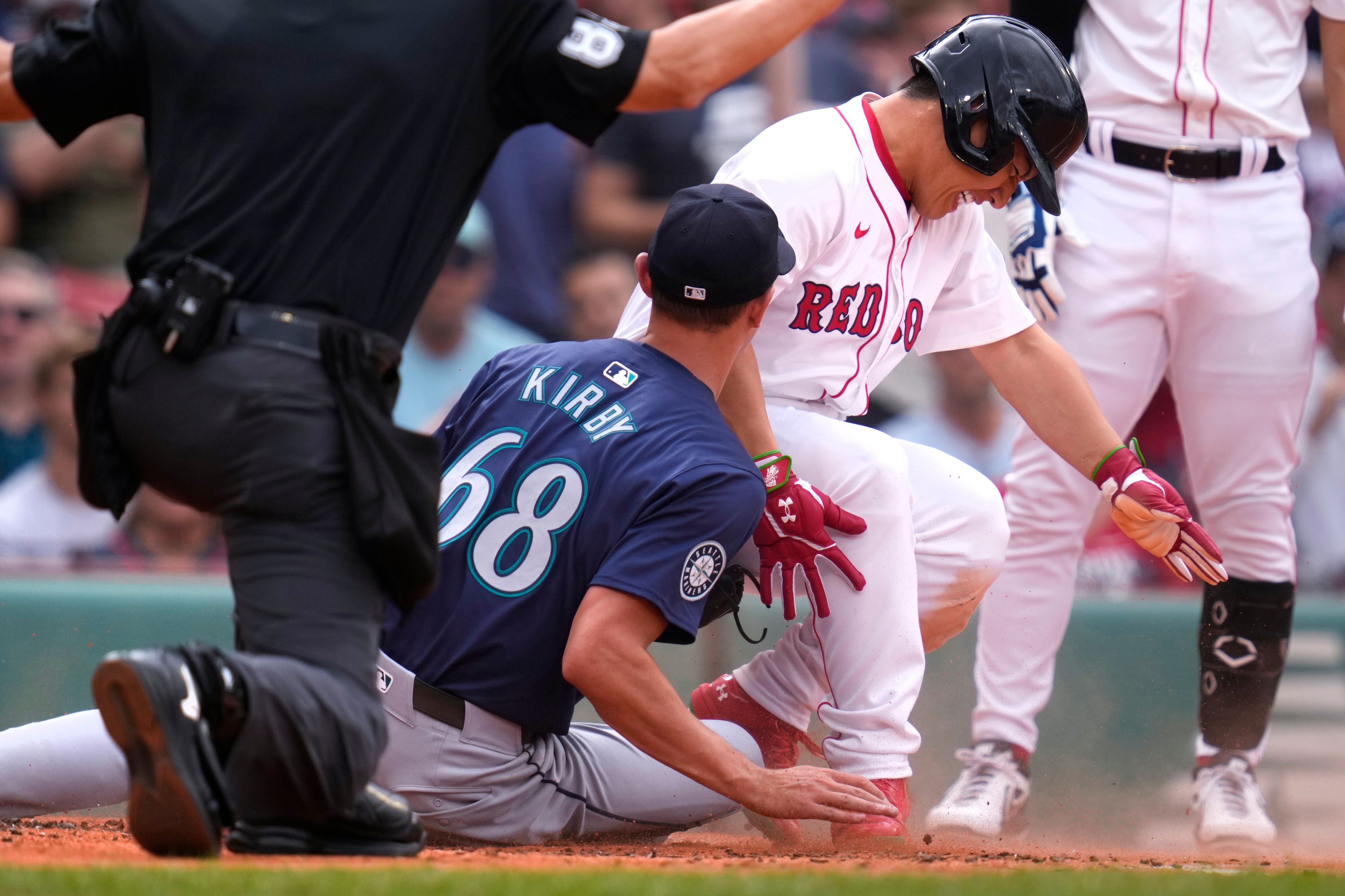 Boston Red Sox's Masataka Yoshida, center, grimaces while colliding with Seattle Mariners pitcher George Kirby (68) while scoring on a wild pitch during the first inning of a baseball game, Wednesday, July 31, 2024, in Boston. (AP Photo/Charles Krupa)