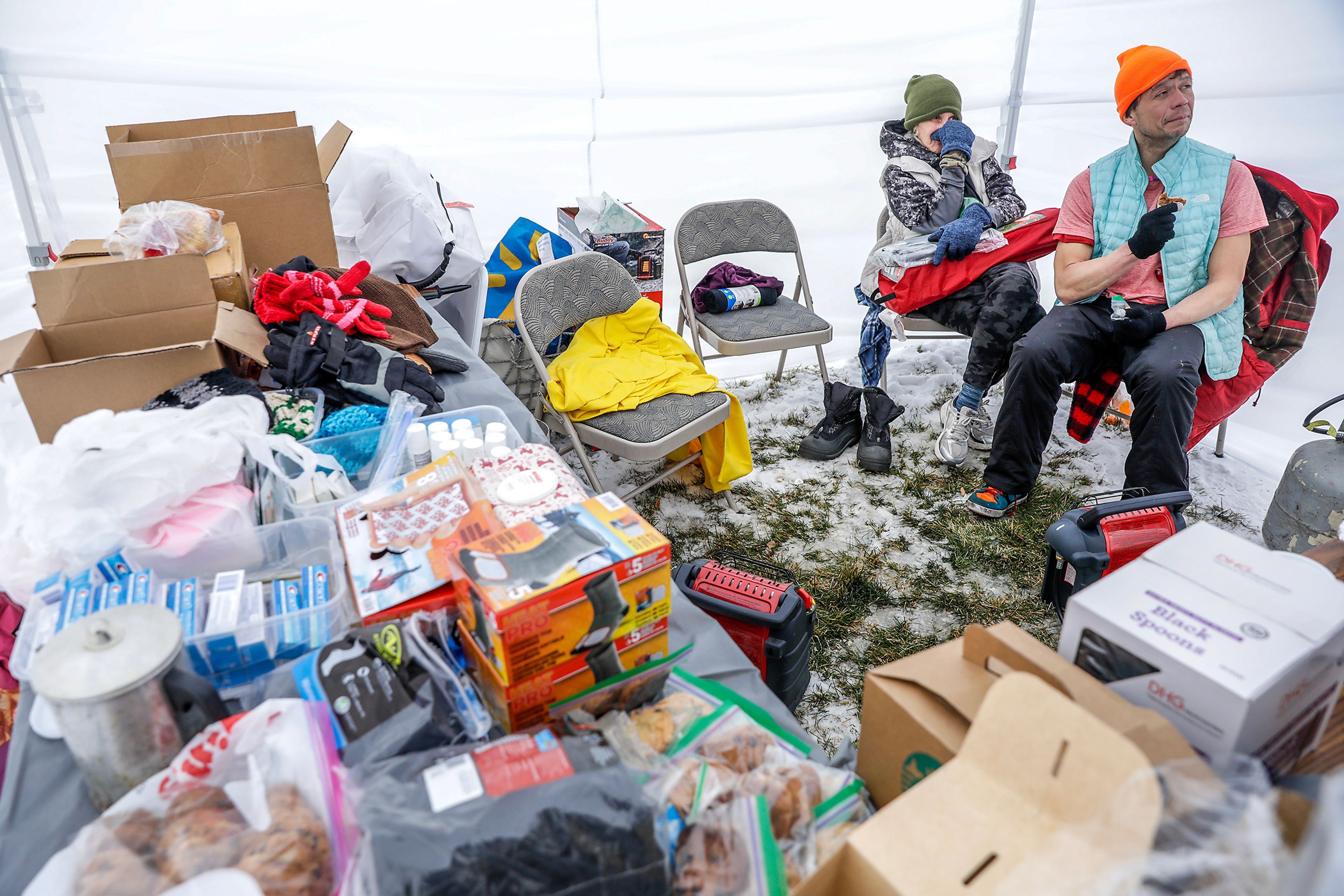 Rocky, right, and another resident of the homeless camp behind Walmart, warm up inside a tent set up by Elves For The Homeless outside the Chef Store on Sunday in Clarkston.