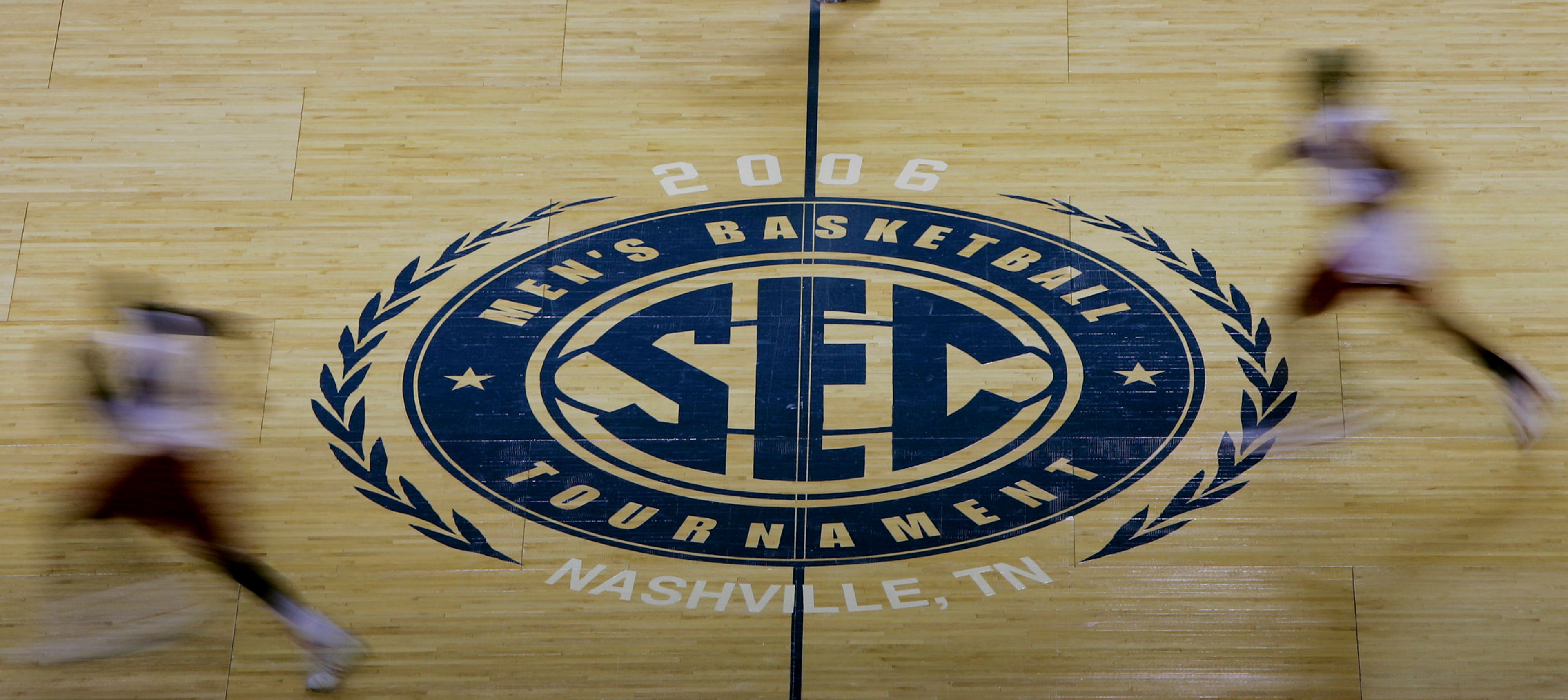 FILE - Arkansas players run past the Southeastern Conference logo during practice for the 2006 SEC men's basketball tournament March 8, 2006, in Nashville, Tenn. The NCAA and the nation's five biggest conferences have agreed to pay nearly $2.8 billion to settle a host of antitrust claims,a monumental decision that sets the stage for a groundbreaking revenue-sharing model that could start directing millions of dollars directly to athletes as soon as the 2025 fall semester.