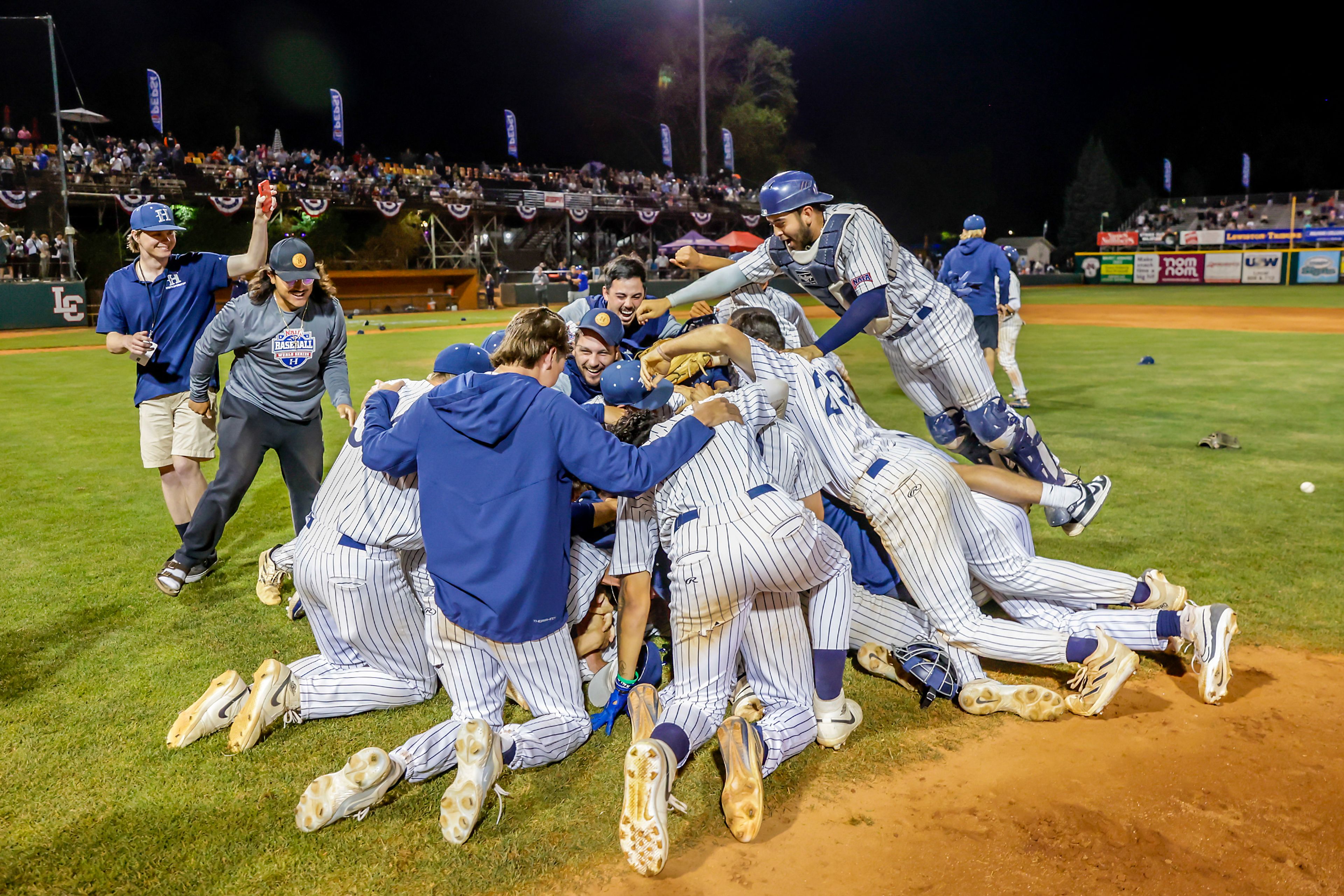 Hope International dogpiles after defeating Tennessee Wesleyan 13-6 in Game 19 of the NAIA World Series at Harris Field Friday in Lewiston.