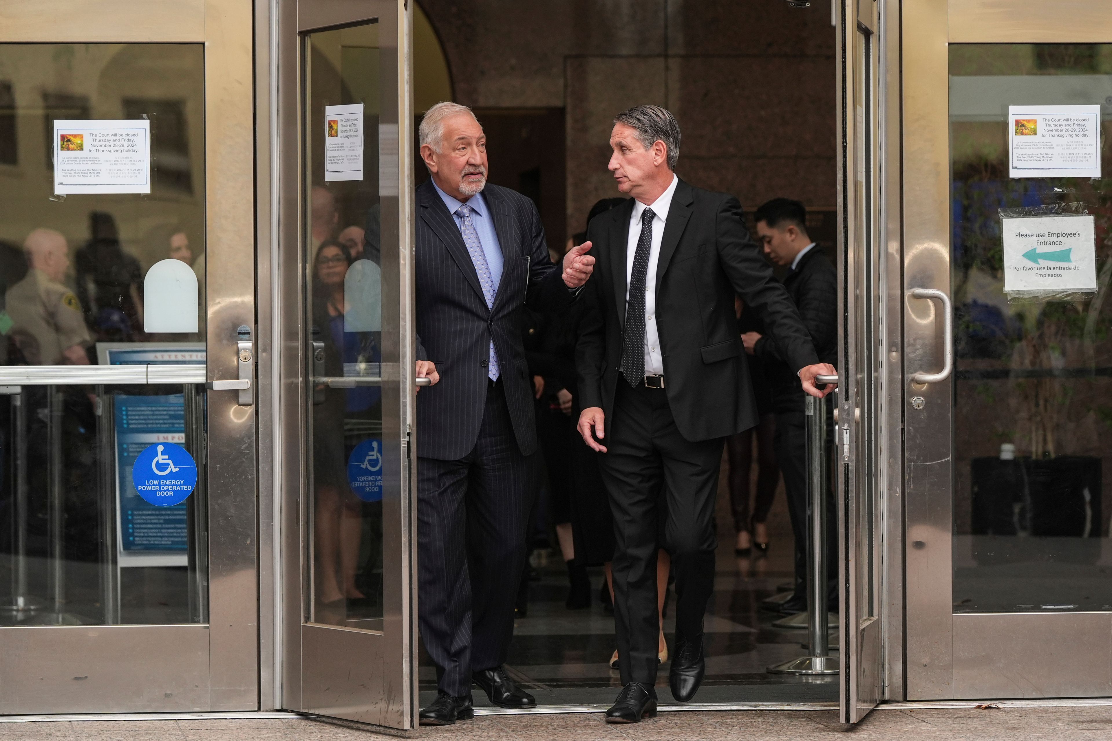 Mark Geragos, left, and Bryan Freedman, attorneys for Erik and Lyle Menendez, and their family members leave a courthouse after a hearing in Los Angeles, Monday, Nov. 25, 2024. (AP Photo/Jae C. Hong)