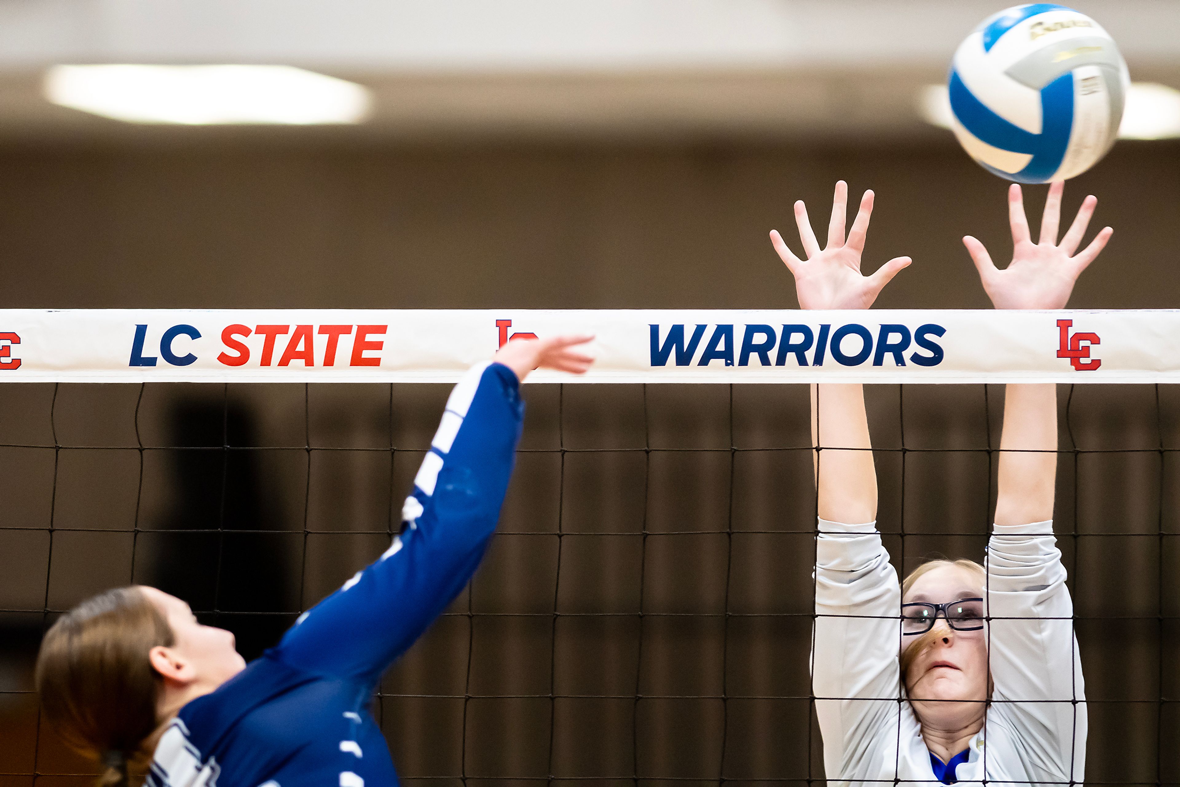 Genesee right side hitter Rylie Baysinger leaps up to block a spike by St. John Bosco's Sarah Waters in a 1A district championship Thursday at the P1FCU Activity Center in Lewiston.,