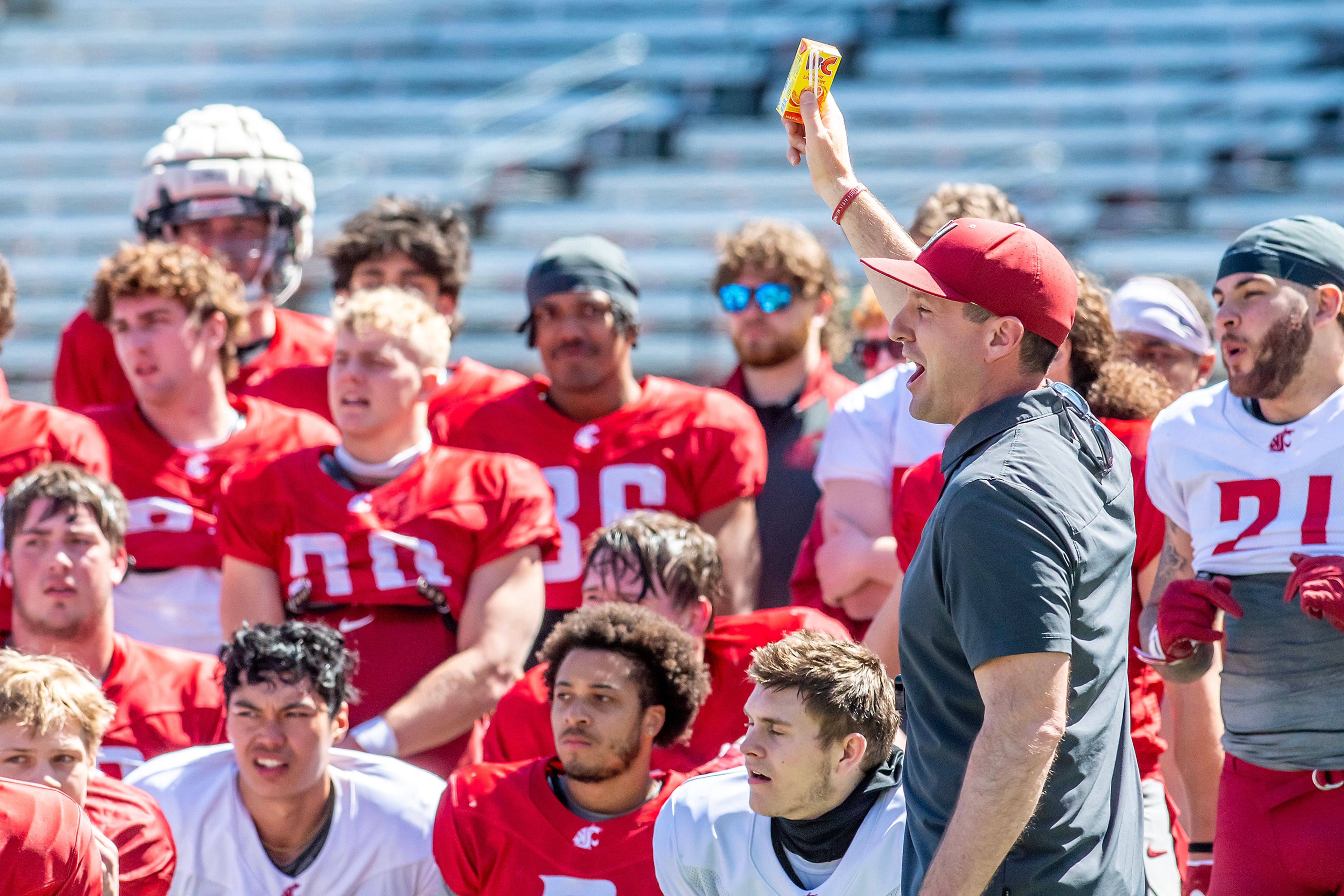 Washington State coach Jake Dickert holds up juice as he and other coaches hand them out following the second scrimmage of spring practice April 20 in Pullman.