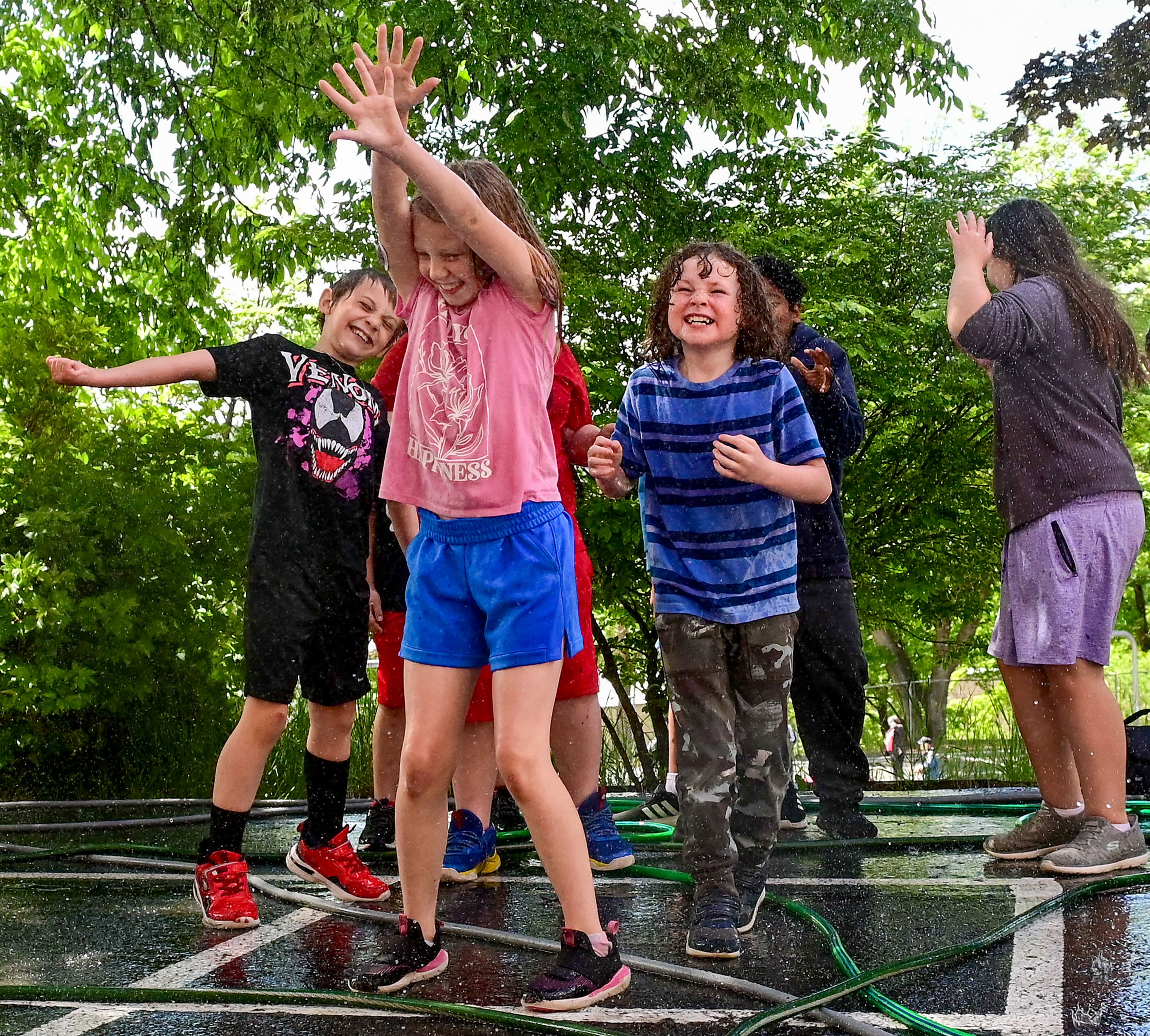 Russell Elementary School third-graders, including Zoey Olson, center, play in the spray of water hoses at Russell’s final day of school field day celebration on Wednesday in Moscow.