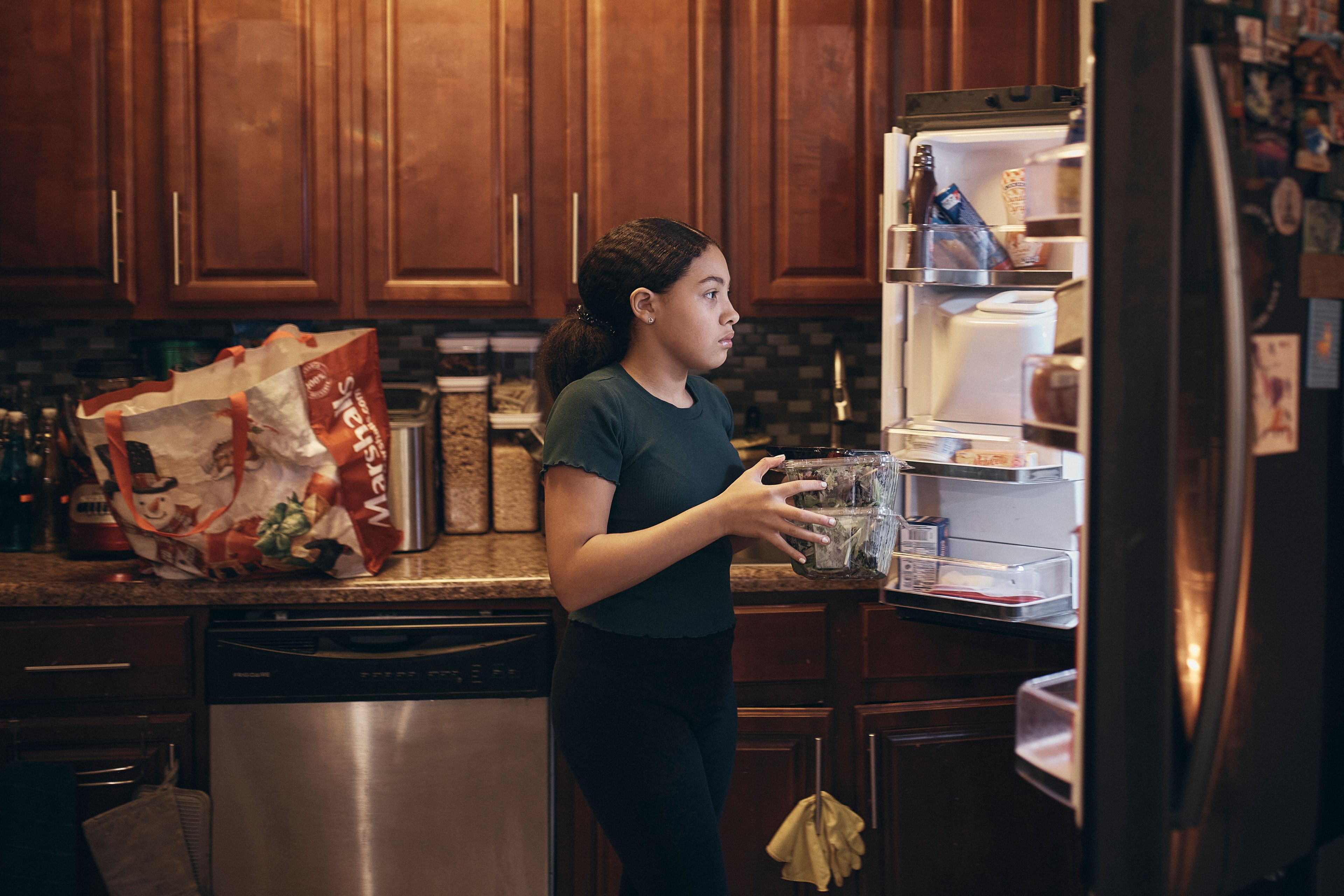 Grace Durham, 11, helps her mother, Elena Romero, not pictured, to put groceries in the refrigerator, Saturday, Jan. 27, 2024, in New York. With the damaging consequences of social media increasingly well documented, many parents are trying to raise their children with restrictions or blanket bans. Teenagers themselves are aware that too much social media is bad for them, and some are initiating social media “cleanses” because of the toll it takes on mental health and grades.