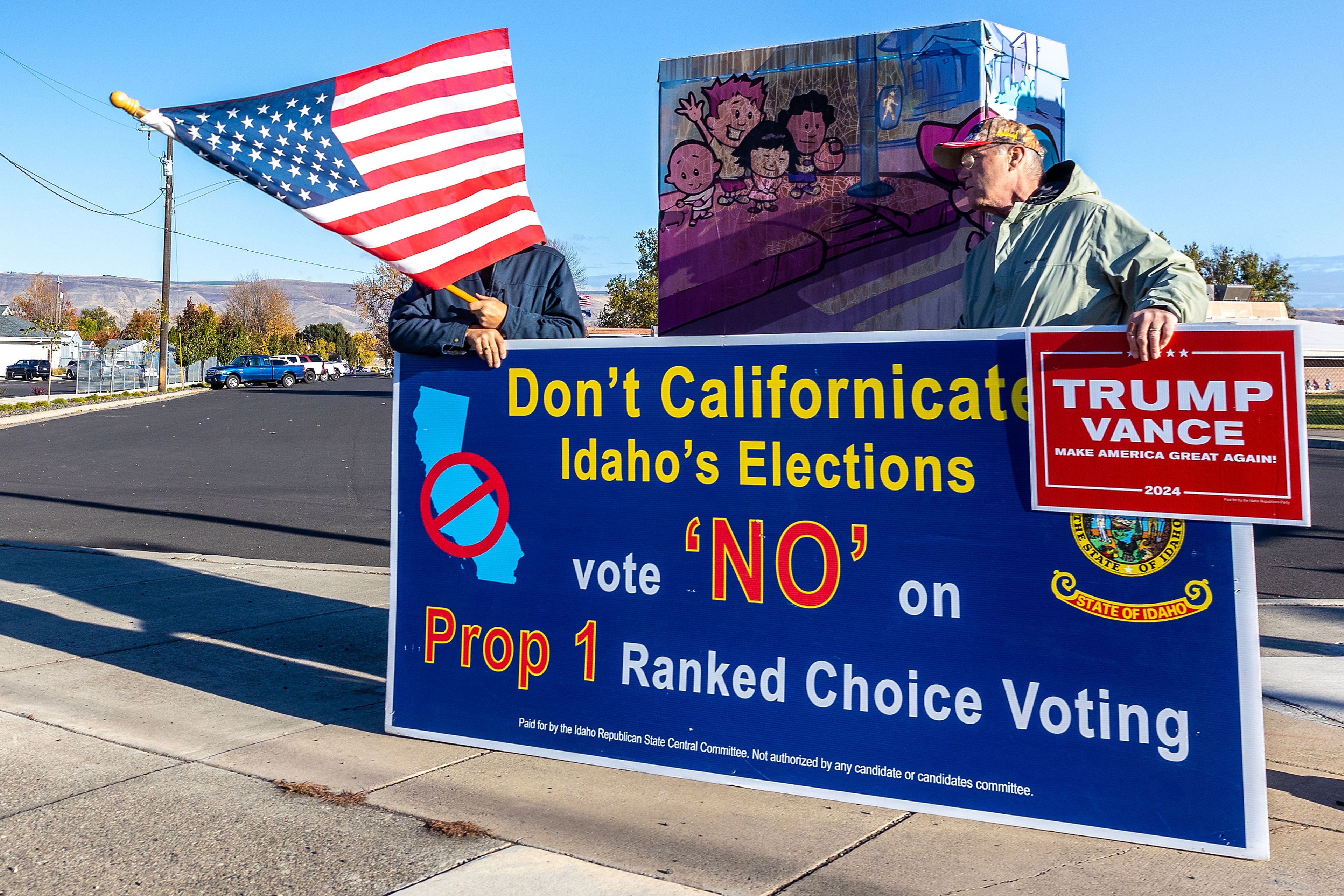 People stand with a sign at the corner of Thain Road and Burrell Avenue Tuesday in Lewiston.