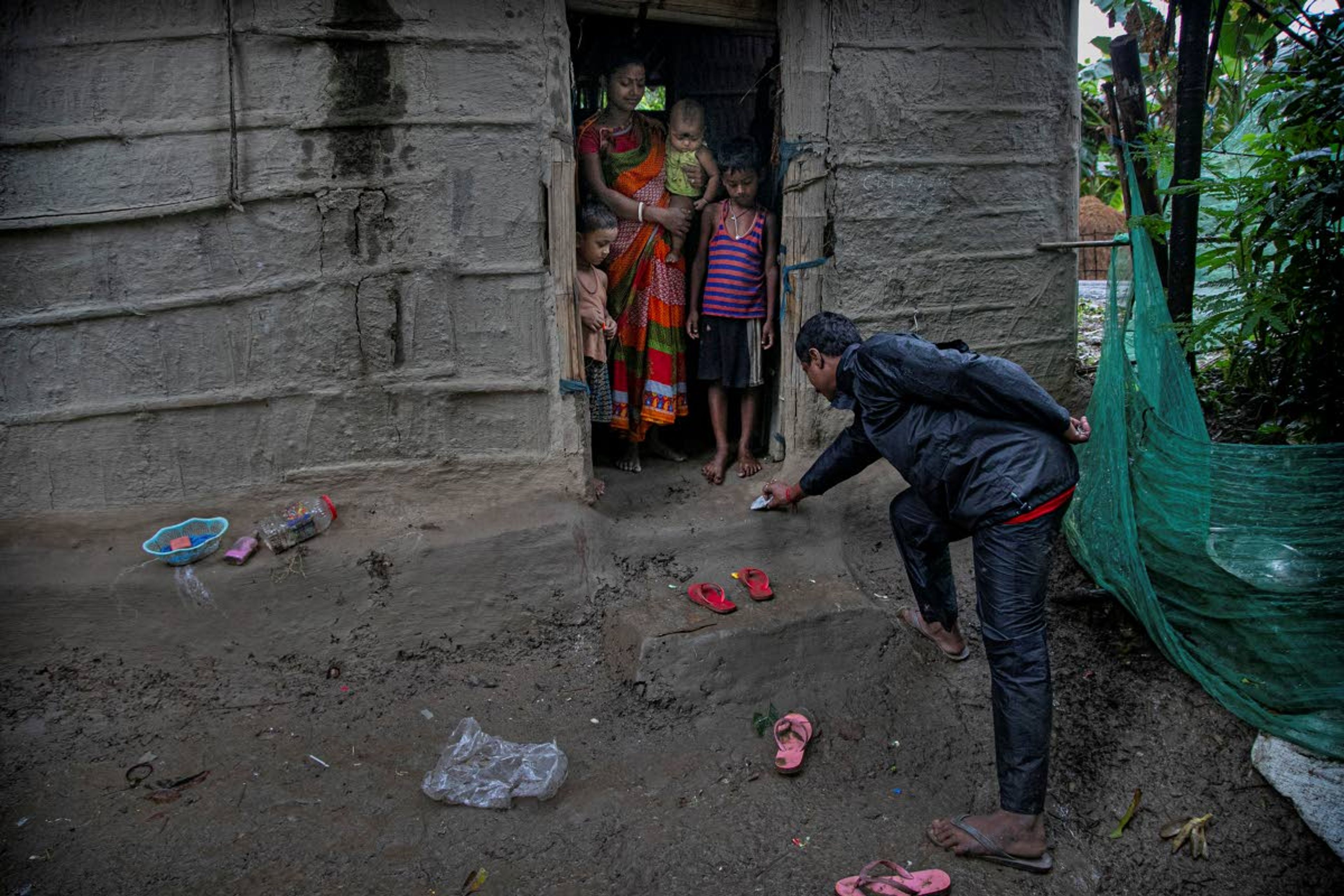 Ramananda Sarkar, 43, places a packet containing money for his wife from a safe distance in Theng Bhanga village, in Morigaon district, India, Tuesday, Sept. 22, 2020. Sarkar thought he had come to terms with his reputation, finally telling his wife what his job was after hiding it for some time. But dealing with corpses is a stigma that's only been made worse by the coronavirus, which has killed more than 100,000 people in India out of 6.4 million reported infections. “I don’t want my sons to become cremators like me," Sarkar said. "I want them to go to school and become good human beings and earn respect from the society, not like me who has to meet his family in the dark.” (AP Photo/Anupam Nath)