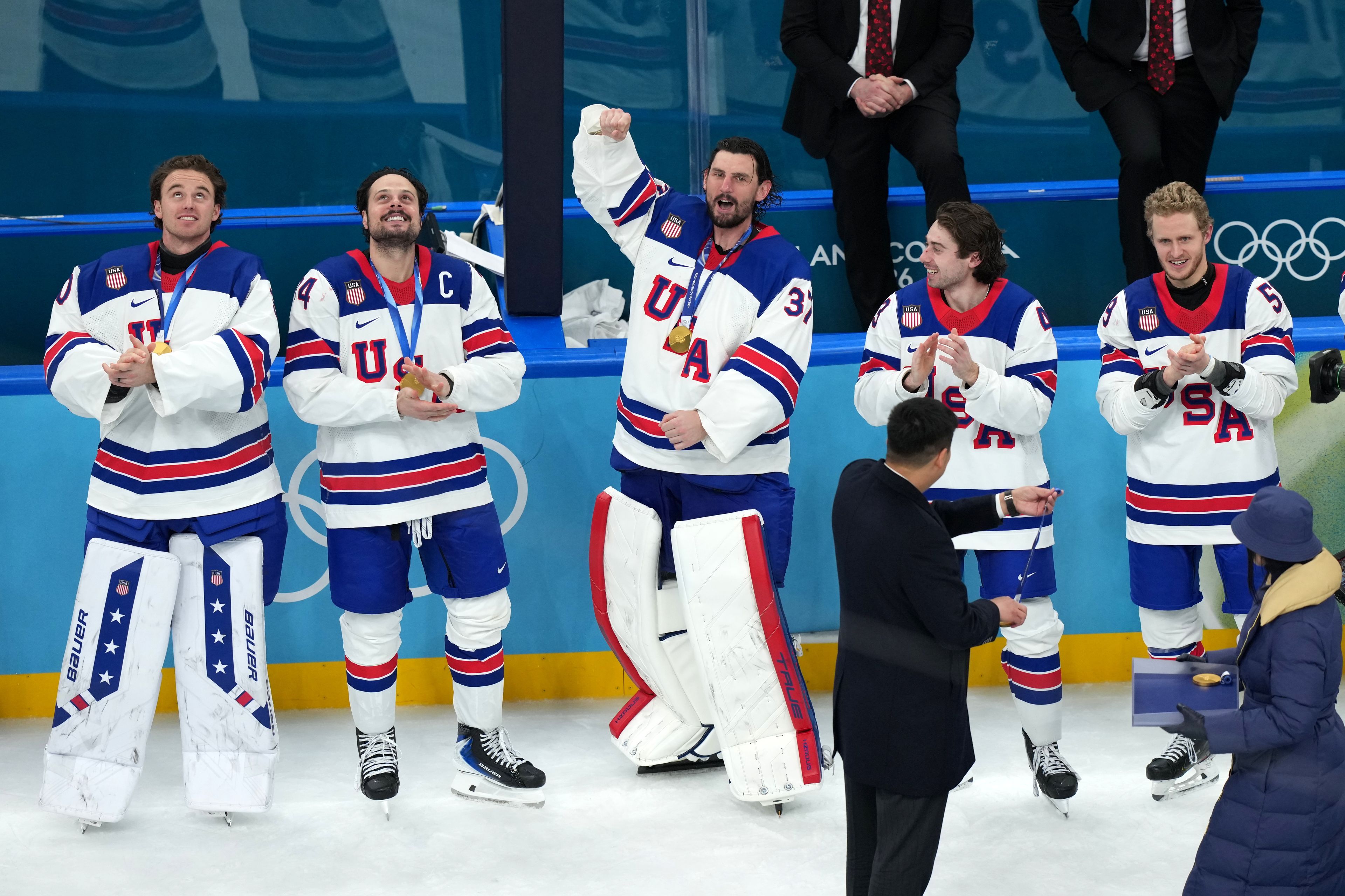 United States goalkeeper Connor Hellebuyck (37) celebrates as players receive their medals after defeating Canada in overtime to win the men’s ice hockey gold medal game at the 2026 Winter Olympics in Milan, Italy, on Sunday.