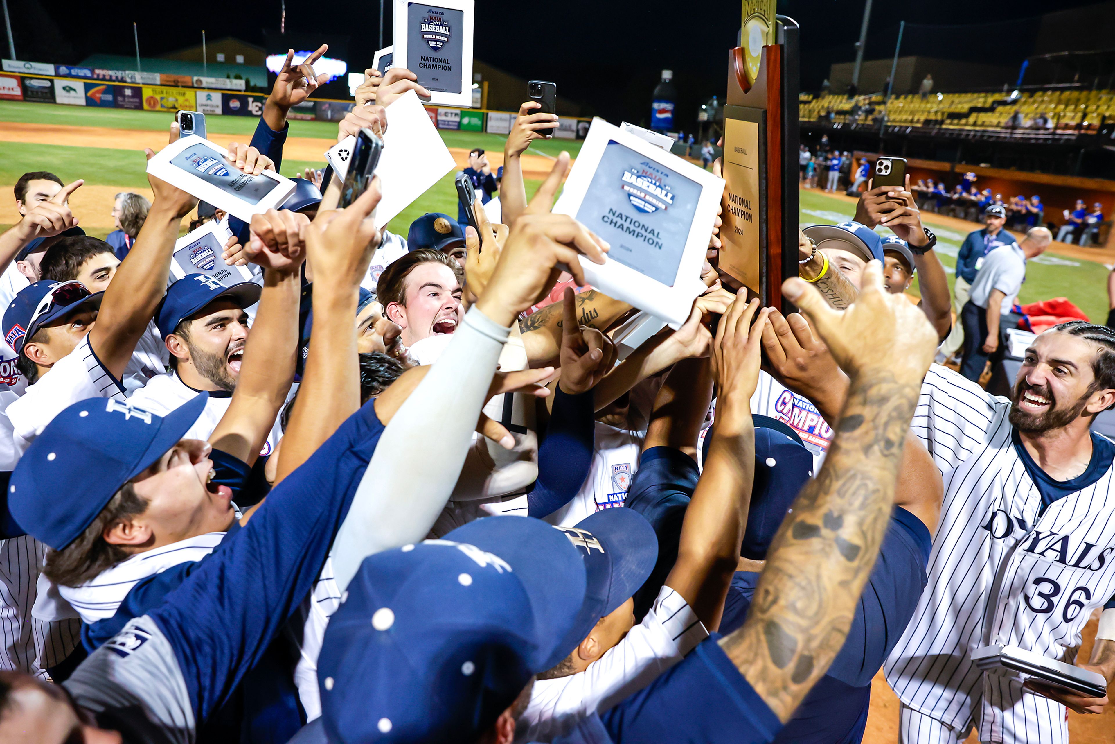 Hope International hoists their trophy after defeating Tennessee Wesleyan 13-6 in Game 19 of the NAIA World Series at Harris Field Friday in Lewiston.