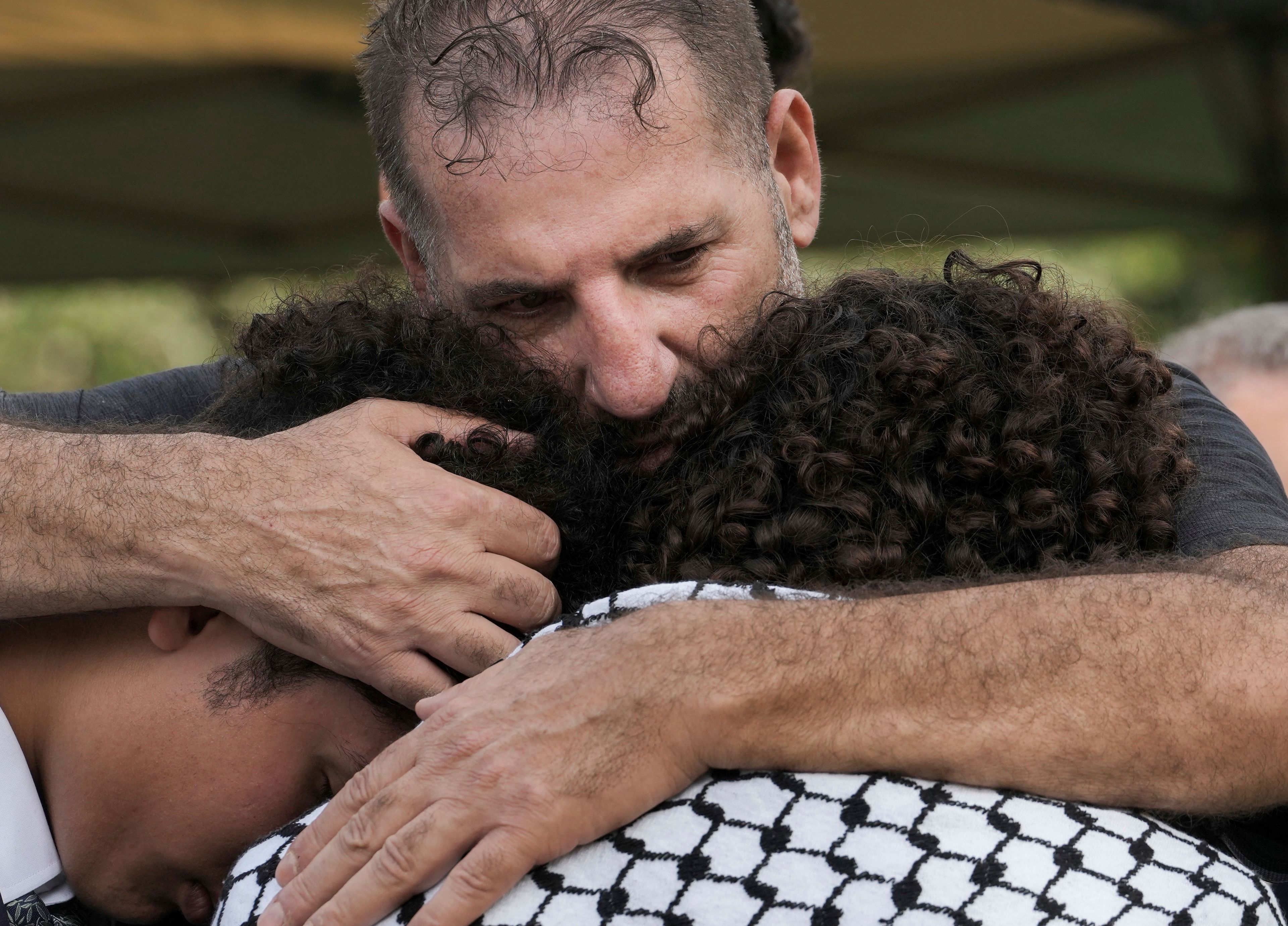 Sam Husseini, brother of slain Harris County Precinct 4 Deputy Constable Maher Husseini, hugs his brother's two sons after his brother's burial, Thursday, Sept. 5, 2024, at Forest Park The Woodlands Funeral Home & Cemetery in The Woodlands, Texas.