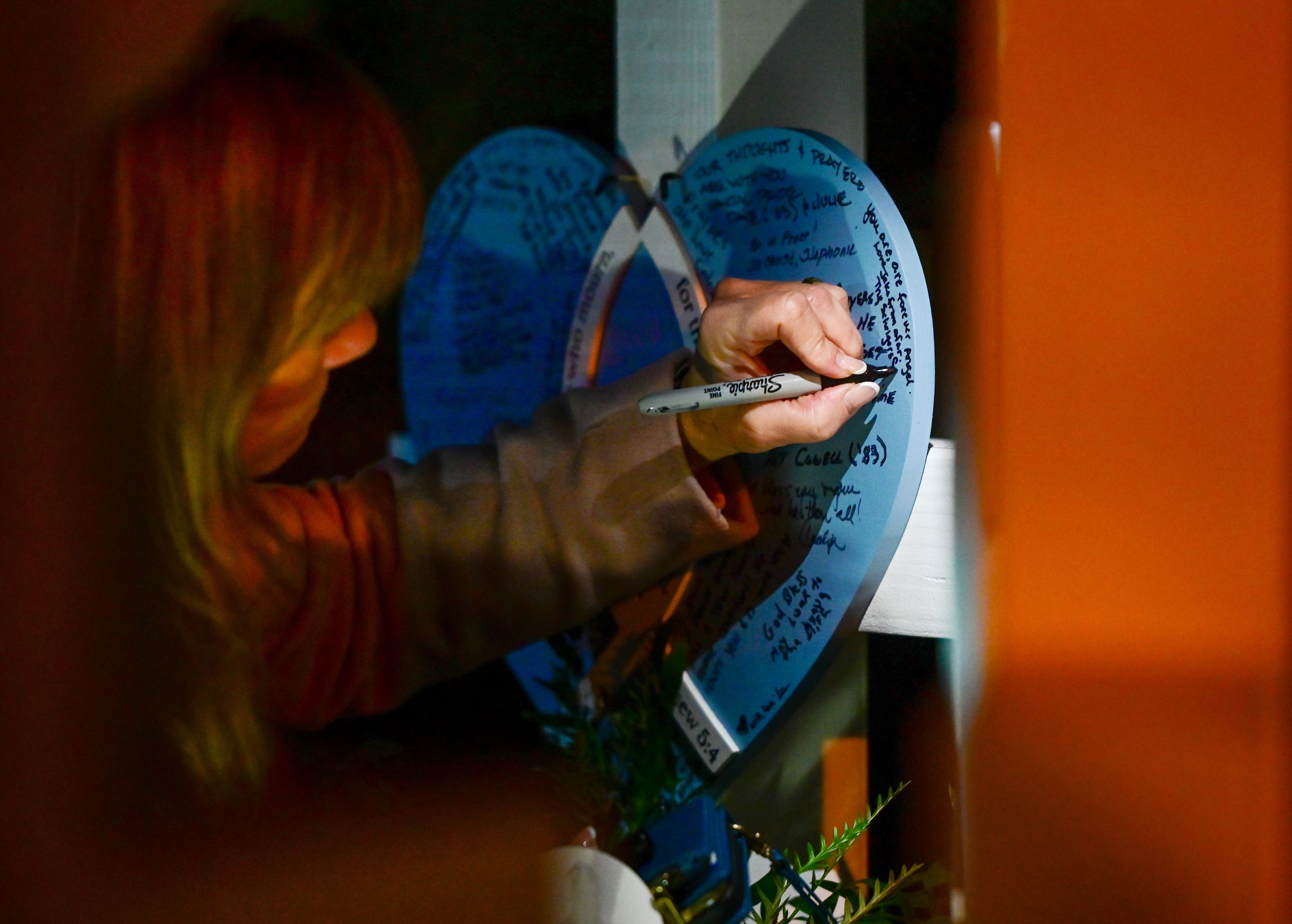 Stacy Schriger on Monday leaves a note on a heart hanging from a cross in memory of Madison Mogen, her son Jake Schriger’s girlfriend who was one of the four University of Idaho students killed a year before in Moscow. Four crosses, one for each student, were brought from Hearts of Mercy & Compassion the vigil held in their memory.