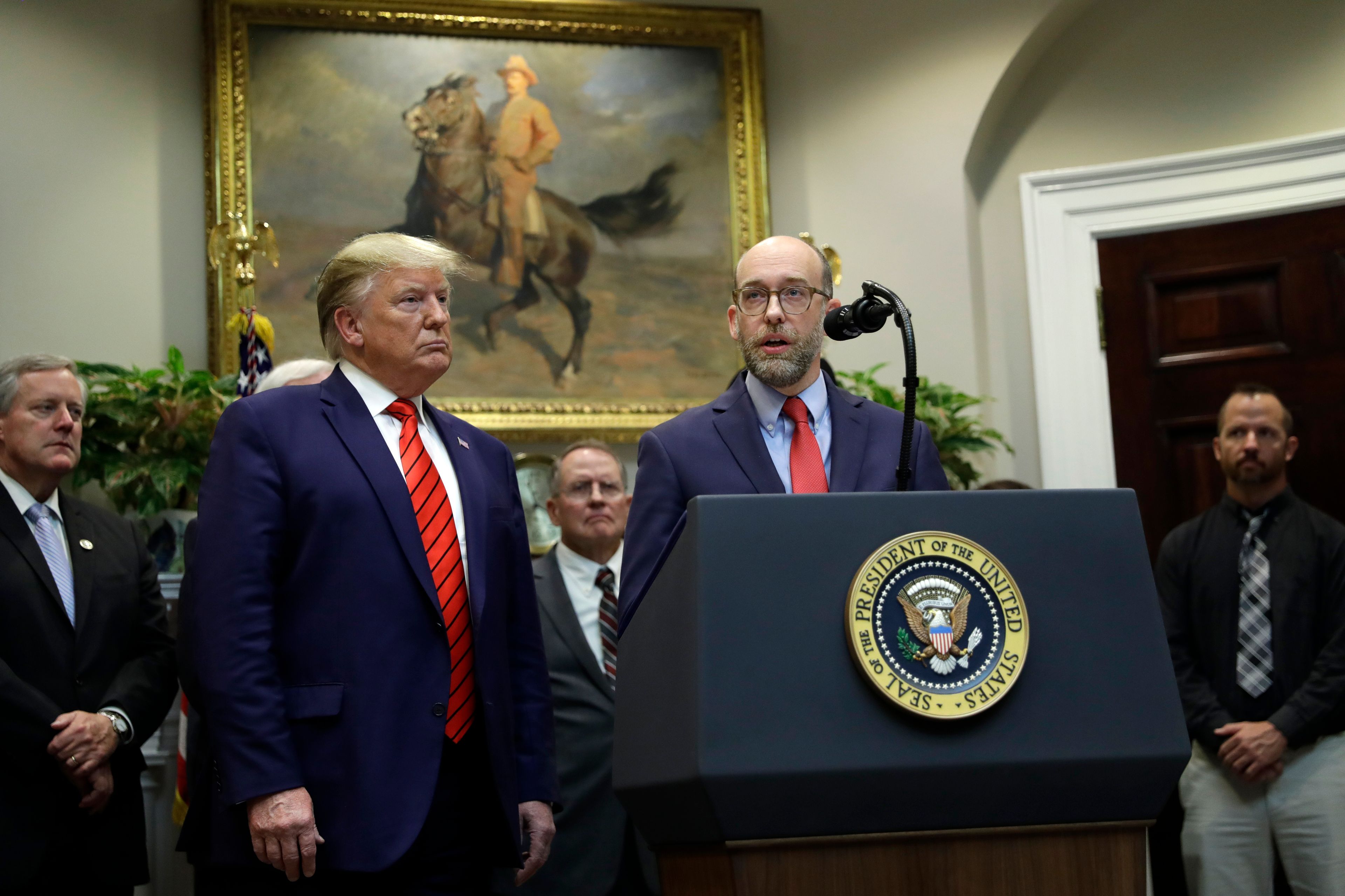 FILE - President Donald Trump, left, listens as acting director of the Office of Management and Budget Russel Vought speaks during an event on "transparency in Federal guidance and enforcement" in the Roosevelt Room of the White House, Oct. 9, 2019, in Washington. (AP Photo/Evan Vucci, File)