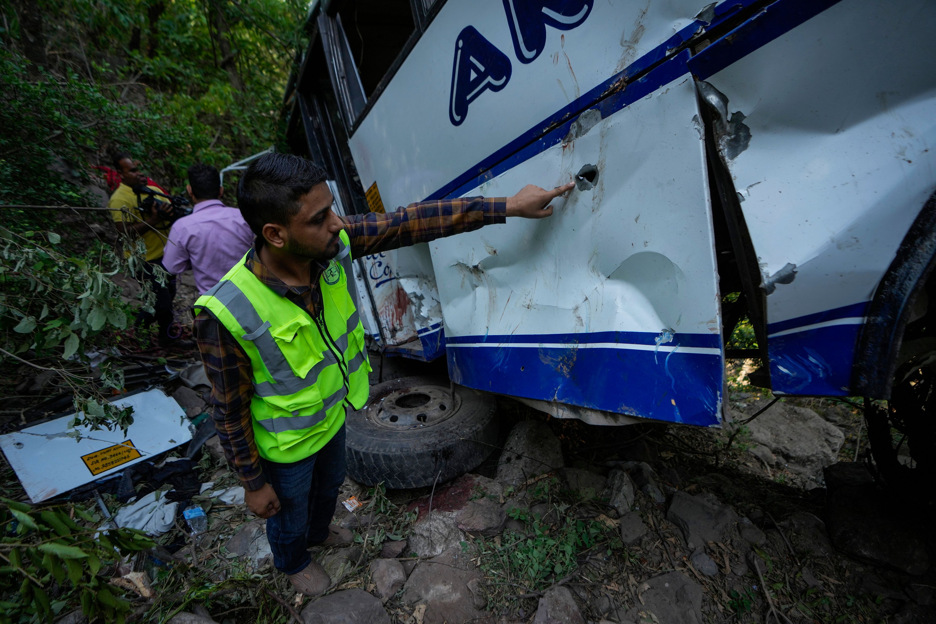 A forensic official inspects a bus that fell into a deep gorge on Sunday after being fired at by suspected militants in Reasi district, Jammu and Kashmir, Monday, June 10, 2024. The bus was carrying pilgrims to the base camp of the famed Hindu temple Mata Vaishno Devi when it came under attack killing at least nine people.