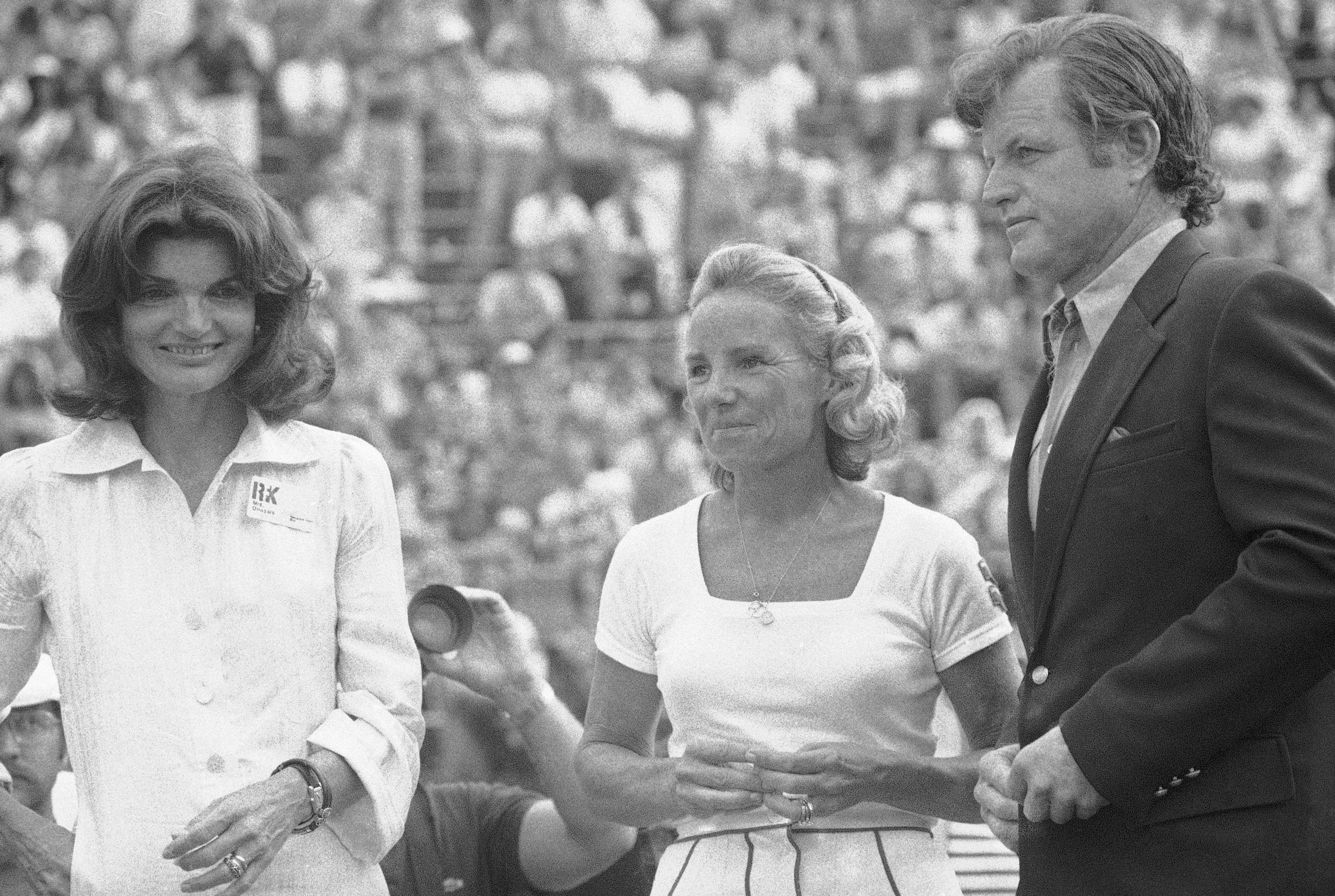 FILE - Mrs. Ethel Kennedy, center, wife of the late Sen. Robert F. Kennedy, stands with her sister-in-law, Mrs. Jacqueline Kennedy Onassis, and brother-in-law Senator Edward Kennedy, at the Robert F. Kennedy Pro-Celebrity Tennis Tournament at New York's Forest Hills Stadium in Queens County, on Aug. 23, 1975. (AP Photo/Suzanne Vlamis, File)