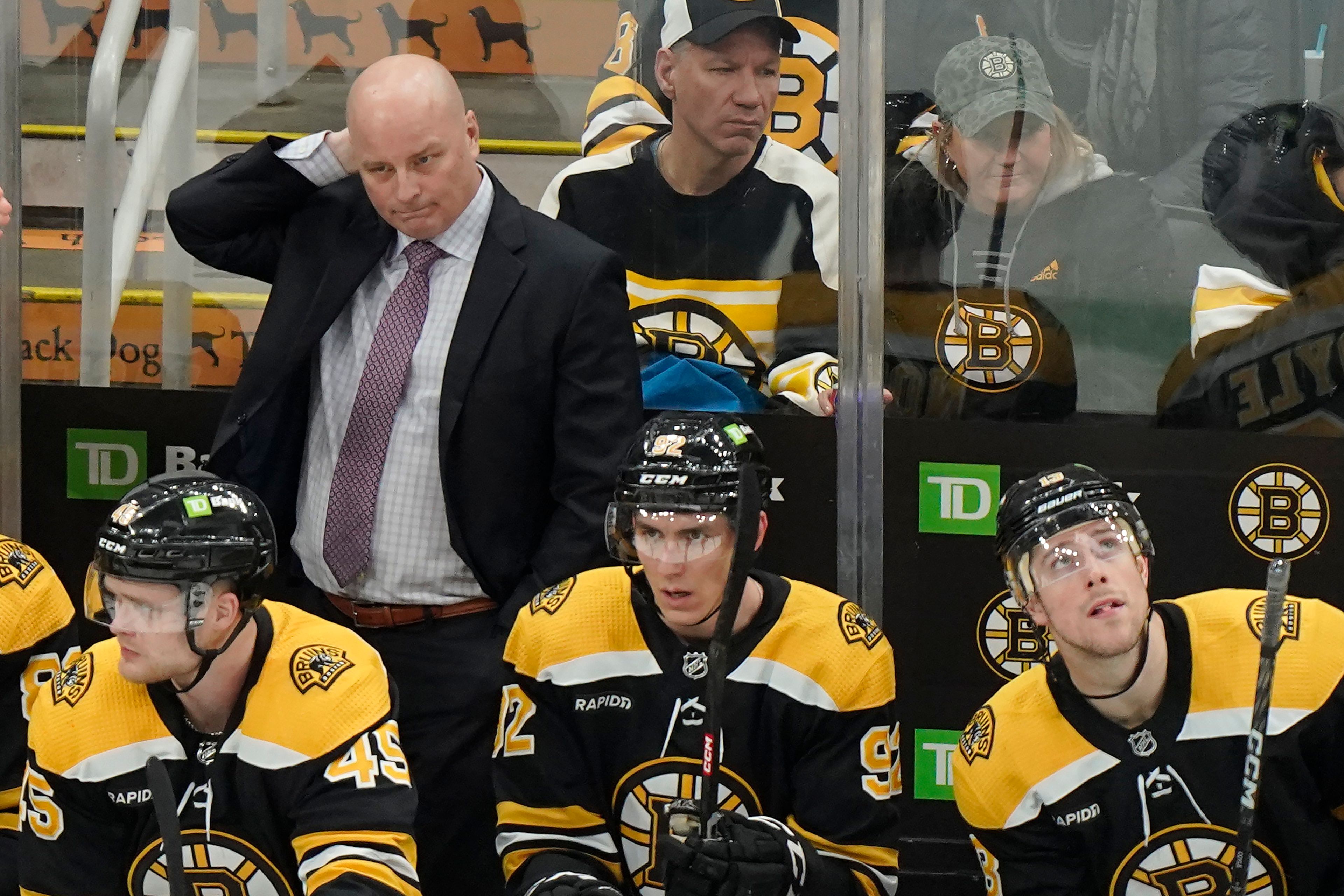 Boston Bruins coach Jim Montgomery, top left, watches from the bench during the first period on the team's NHL hockey game against the Seattle Kraken, Thursday, Jan. 12, 2023, in Boston. (AP Photo/Steven Senne)