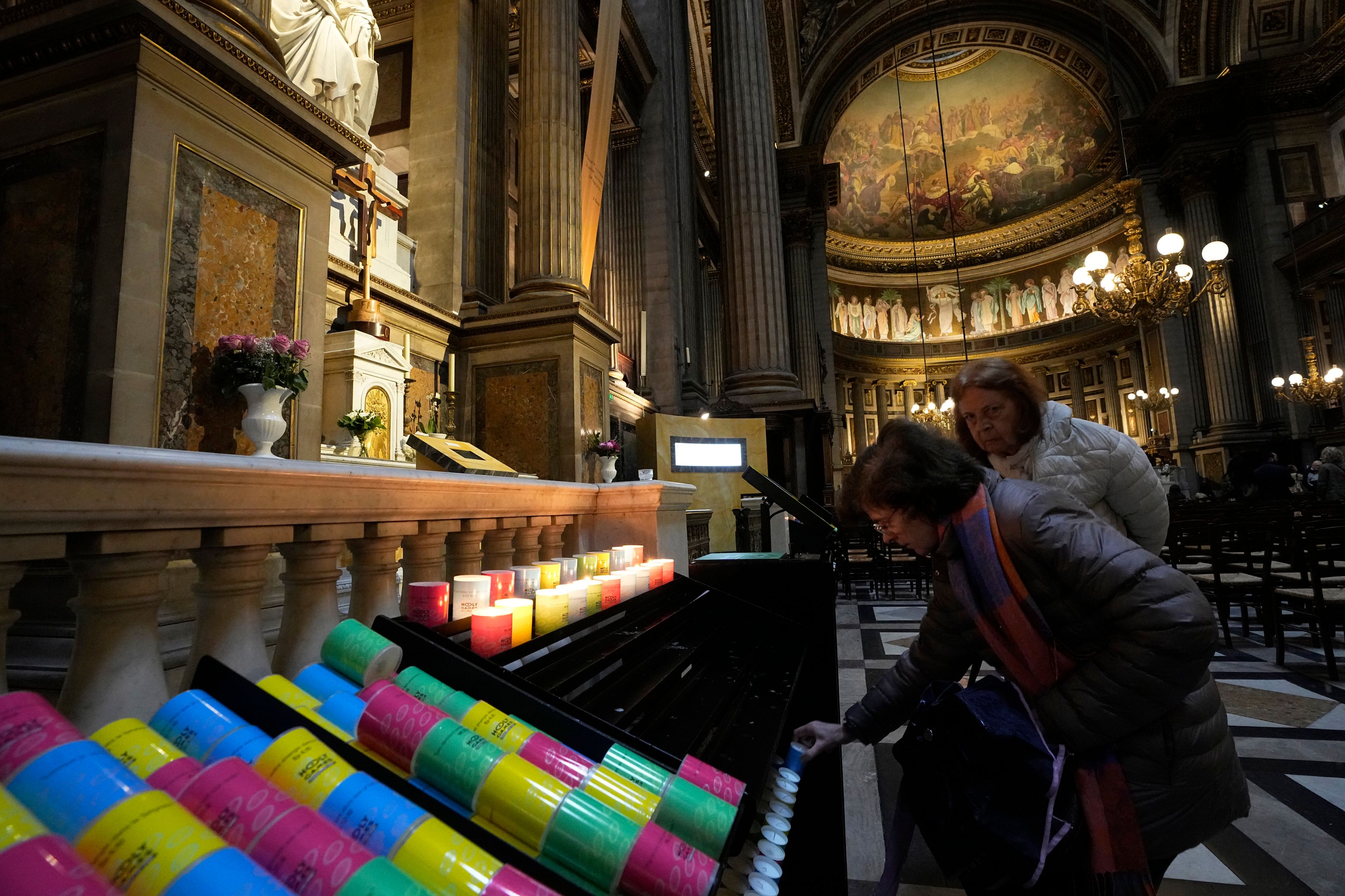 Women light candles at the "Our Lady of Athletes" chapel inside the Madeleine church, Thursday, May 30, 2024 in Paris. France's Catholic Bishops Conference has launched a nationwide "Holy Games" initiative. Since last September, it has set up the "Our Lady of Athletes" chapel in an iconic downtown Paris church, La Madeleine.