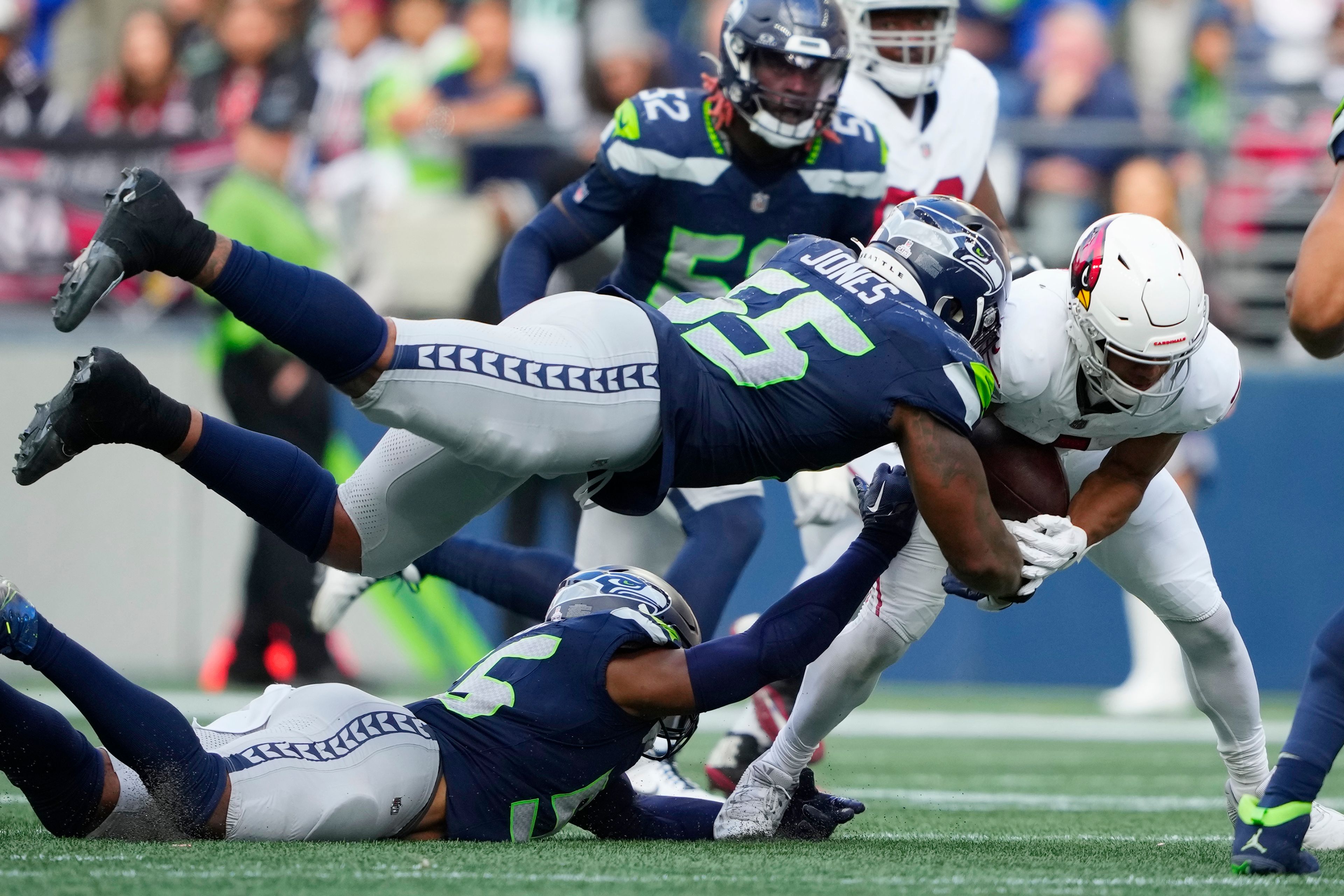 Seattle Seahawks defensive end Dre'Mont Jones (55) and Seahawks linebacker Jordyn Brooks takes down Arizona Cardinals quarterback Joshua Dobbs, right, during the second half of an NFL football game Sunday, Oct. 22, 2023, in Seattle. (AP Photo/Lindsey Wasson)