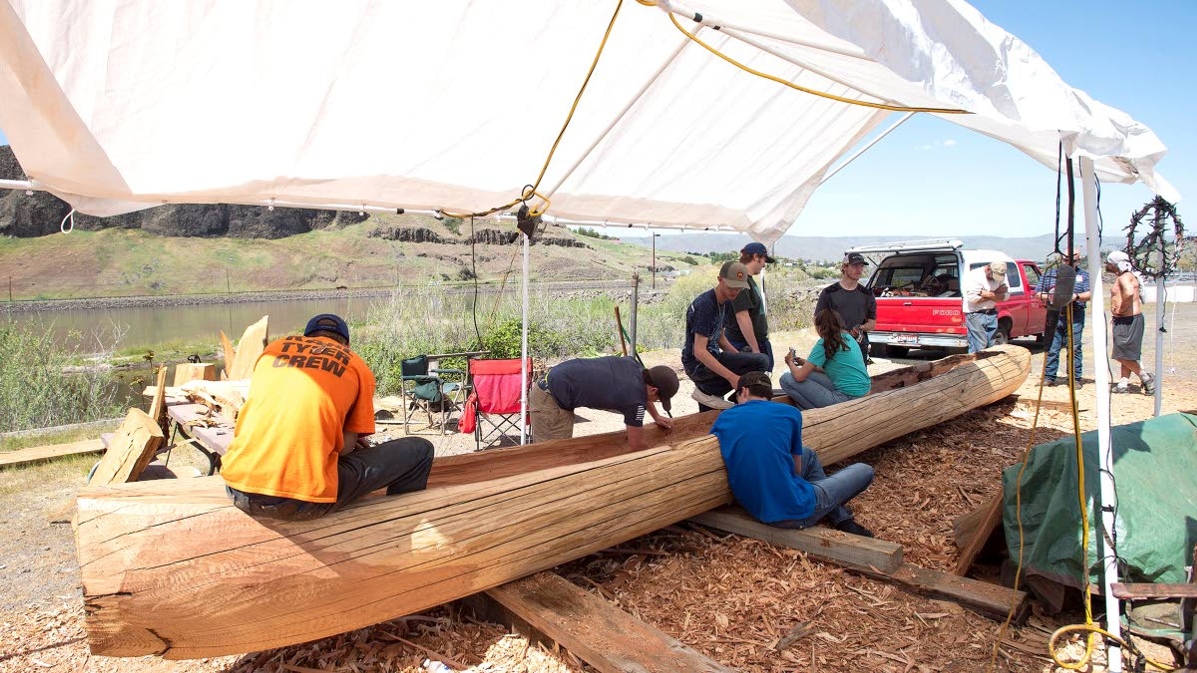 Lewiston High School carpentry students work on carving a large cedar log into a canoe Monday at Hells Gate State Park.