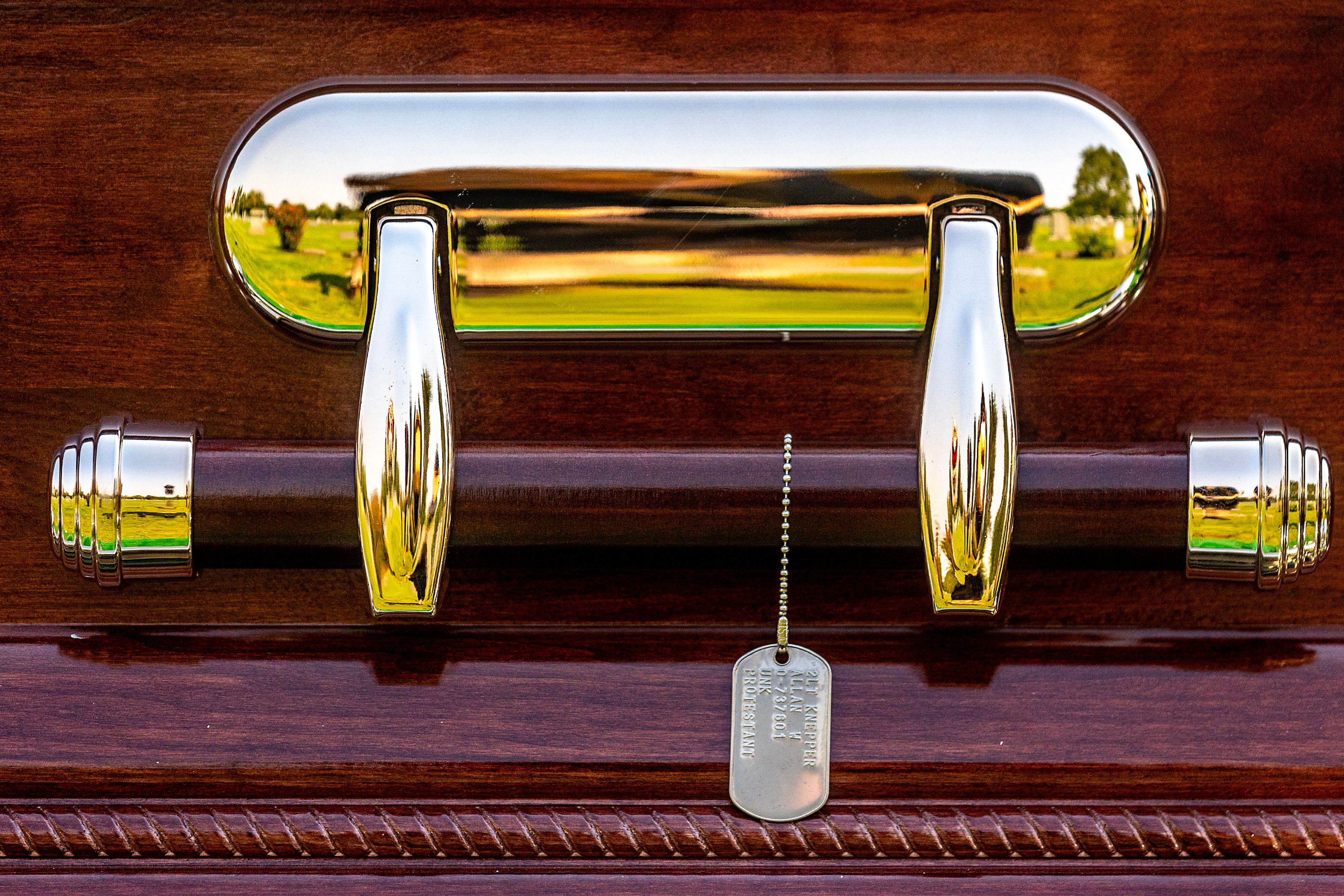 A dog tag hangs off the handle of Allan Knepper’s casket at his funeral Thursday at the Normal Hill Cemetery in Lewiston.