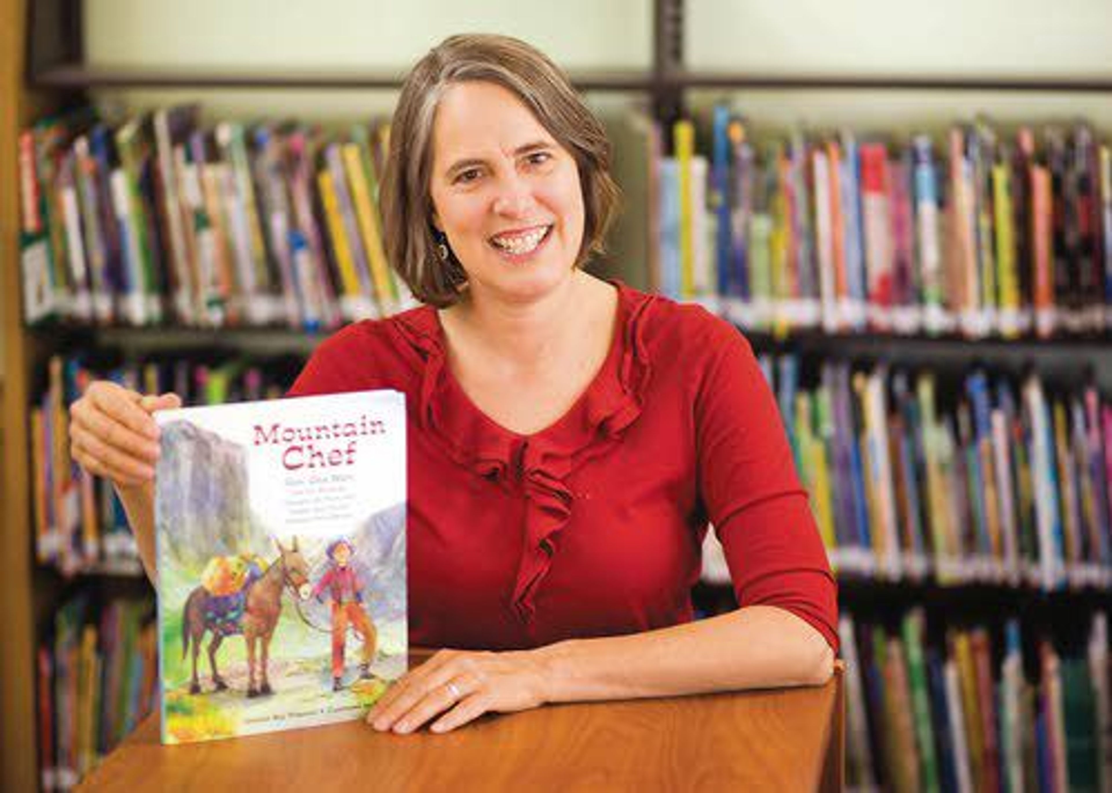 Daily News file photo/Geoff CrimminsMoscow author Annette Pimentel holds a copy of her new book “Mountain Chef,” which was released this month. The nonfiction children’s book tells the story of Tie Sing, a Chinese backcountry cook who helped inspire the creation of the National Park Service.