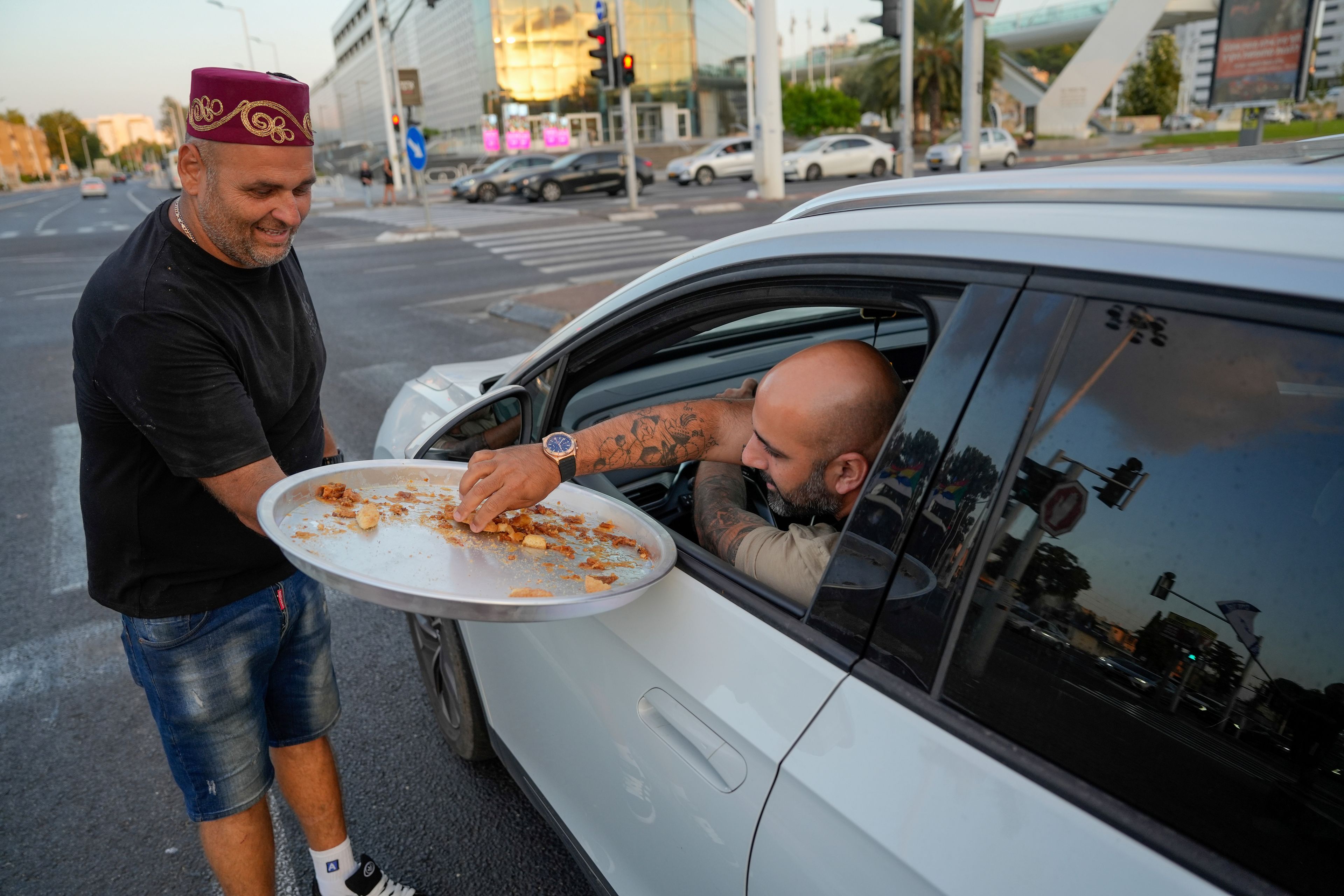 Israeli man Avi Azran distributes sweets to celebrate the news of the death of Hezbollah leader Hassan Nasrallah in the northern Israeli city of Nahariya, Saturday, Sept. 28, 2024. (AP Photo/Baz Ratner)