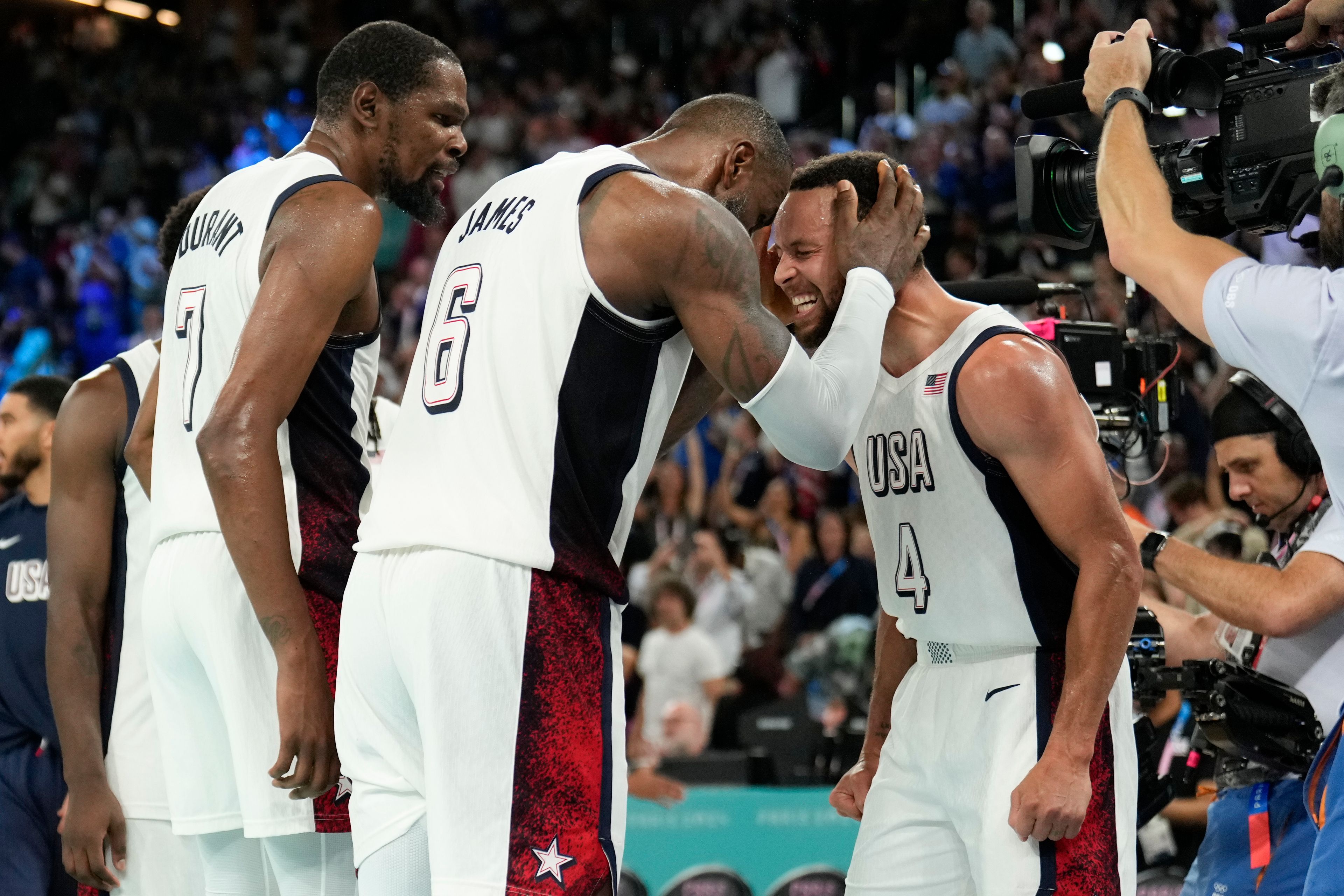 United States' Kevin Durant (7), LeBron James (6) and Steph Curry (4) celebrate after beating Serbia during a men's semifinals basketball game at Bercy Arena at the 2024 Summer Olympics, Thursday, Aug. 8, 2024, in Paris, France. (AP Photo/Mark J. Terrill)