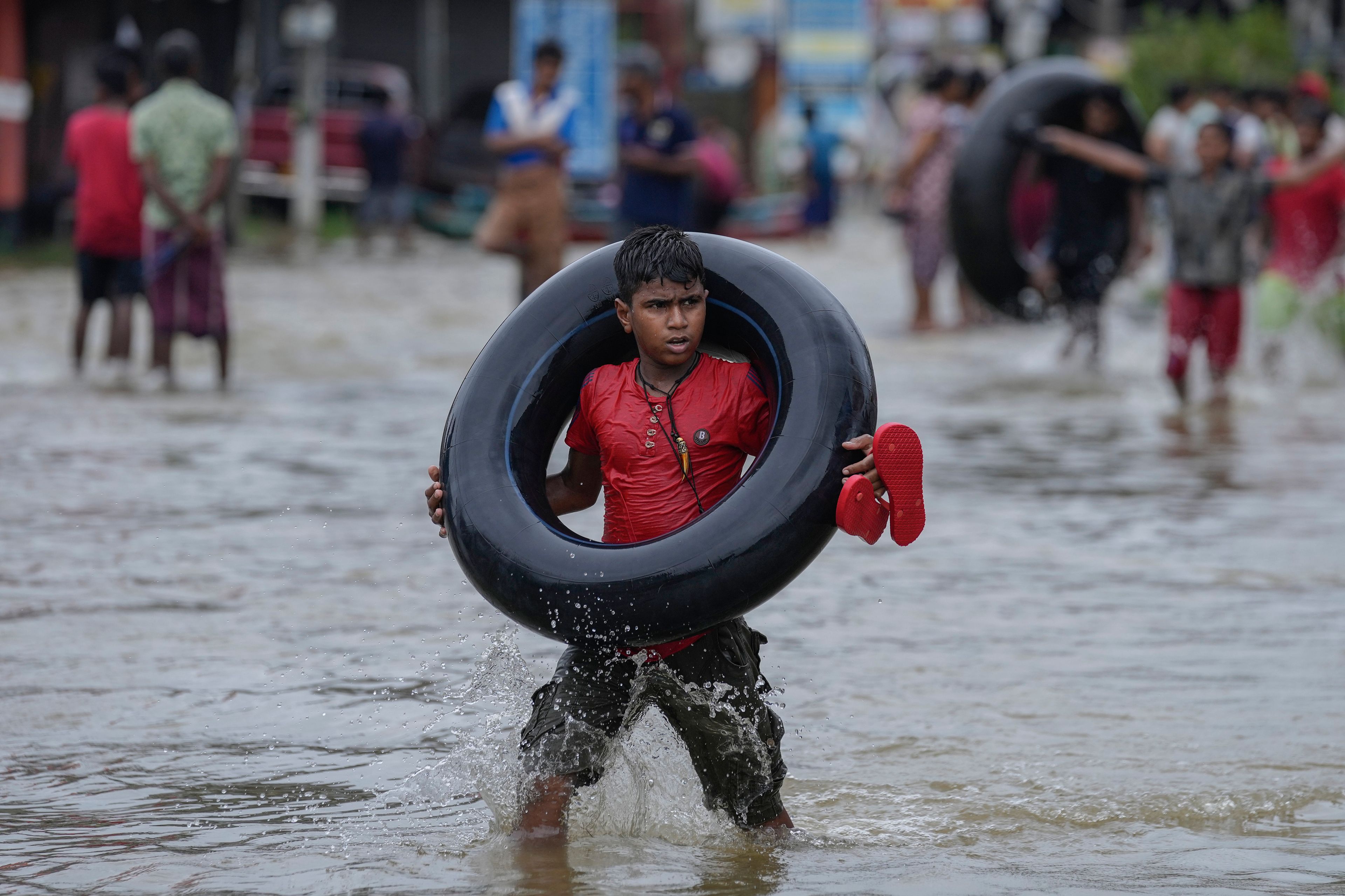 A boy carries an inflatable rubber tube as he wades through a flooded street in Biyagama, a suburb of Colombo, Sri Lanka, Monday, Jun. 3, 2023. Sri Lanka closed schools on Monday as heavy rains triggered floods and mudslides in many parts of the island nation, killing at least 10 people while six others have gone missing, officials said.