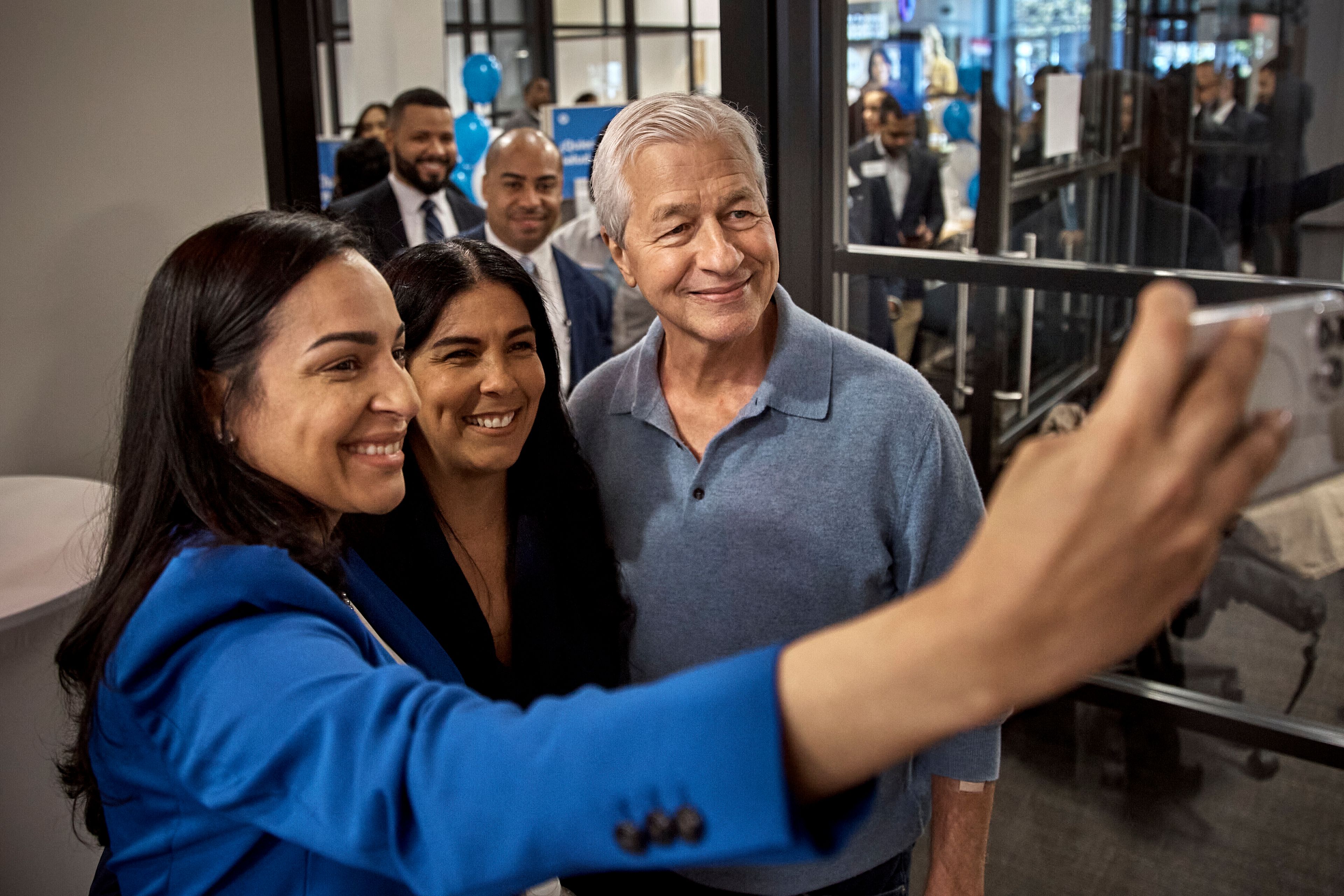 FILE - Jamie Dimon, CEO and chairman of JPMorgan Chase, center right, poses for a selfie with employees during the community branch opening in the Bronx borough of New York, on April 26, 2024. The nation's largest banks are spending hundreds of millions of dollars on refurbishing old locations or building new ones, and in the process changing the look, feel and purpose of the local bank branch.