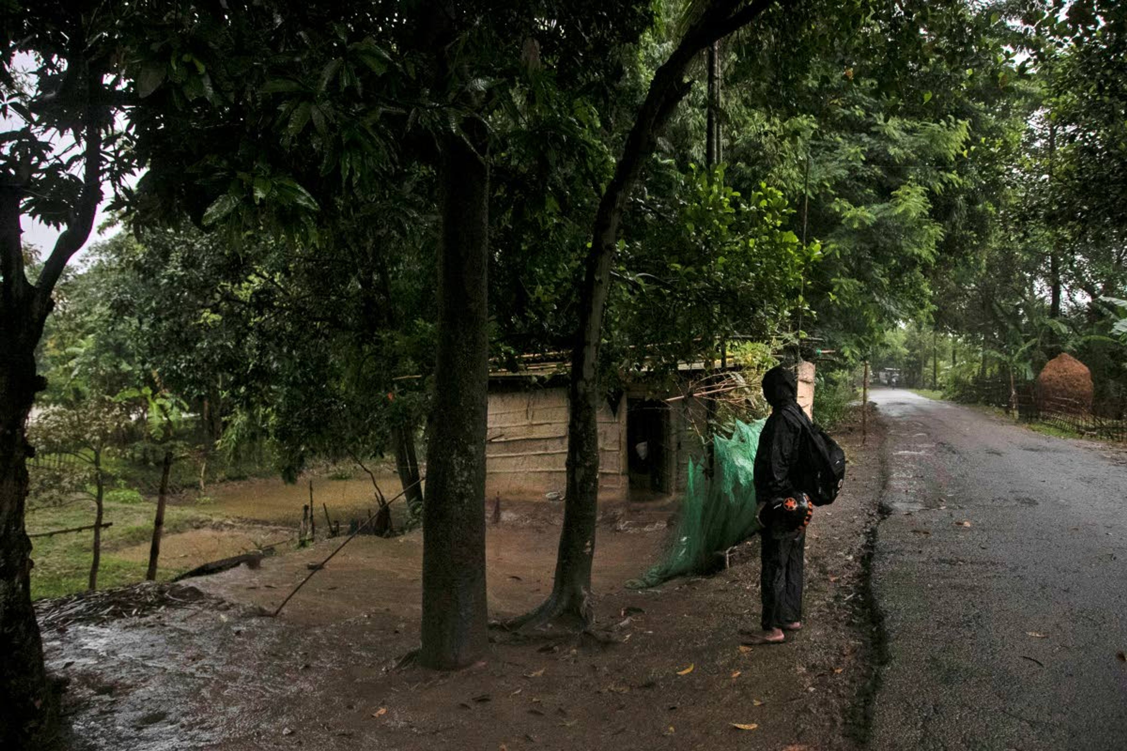 Ramananda Sarkar, 43, calls out to his wife from a road after reaching his house in Theng Bhanga village, in Morigaon district, India, Tuesday, Sept. 22, 2020. Sarkar, who was deep in debt and desperate for money, took the job of lighting funeral pyres after failing to pay back a loan he'd taken to start selling sugarcane juice on a wooden cart. Dealing with corpses is a stigma that's only been made worse by the coronavirus, which has killed more than 100,000 people in India out of 6.4 million reported infections. After a month and a half of not seeing his wife and three sons, Sarkar snuck into his village in the middle of a recent rainy night and was able to spend 15 minutes with them and leave them some money. (AP Photo/Anupam Nath)