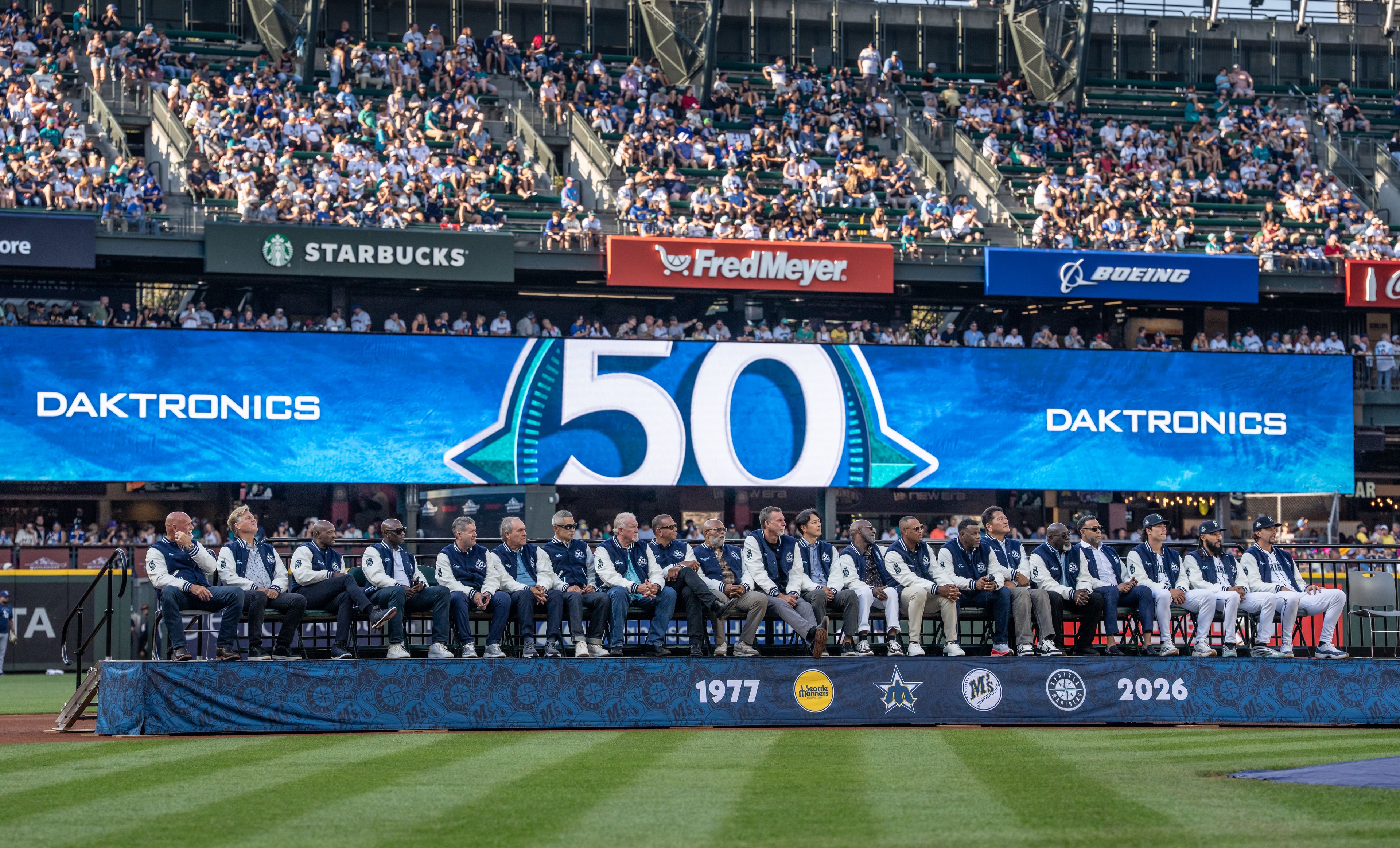 Several current and former Mariners players sit on the field during a ceremony celebrating the team’s 50th anniversary before a baseball game between the Mariners and the Rays on Saturday in Seattle. 